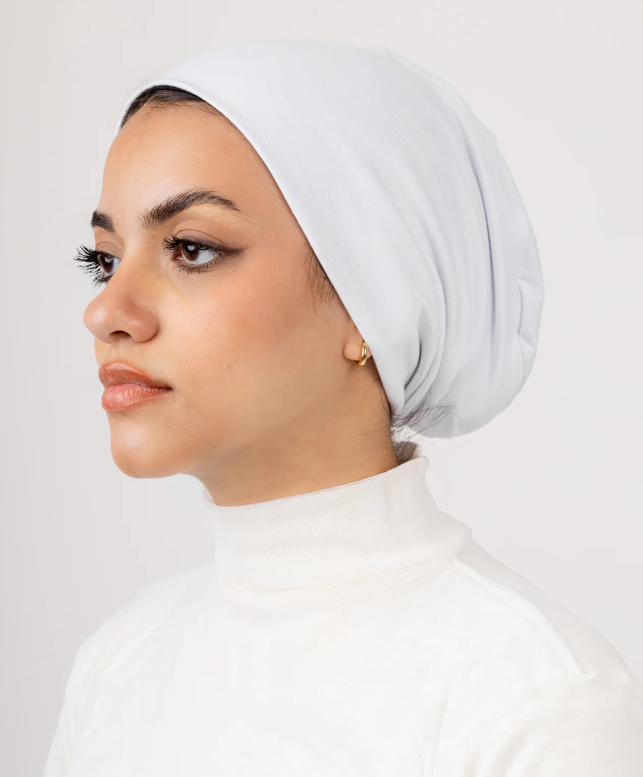 Model wearing Jaida White No Thread Underscarf (undercap), side profile, smooth seamless finish under hijab.