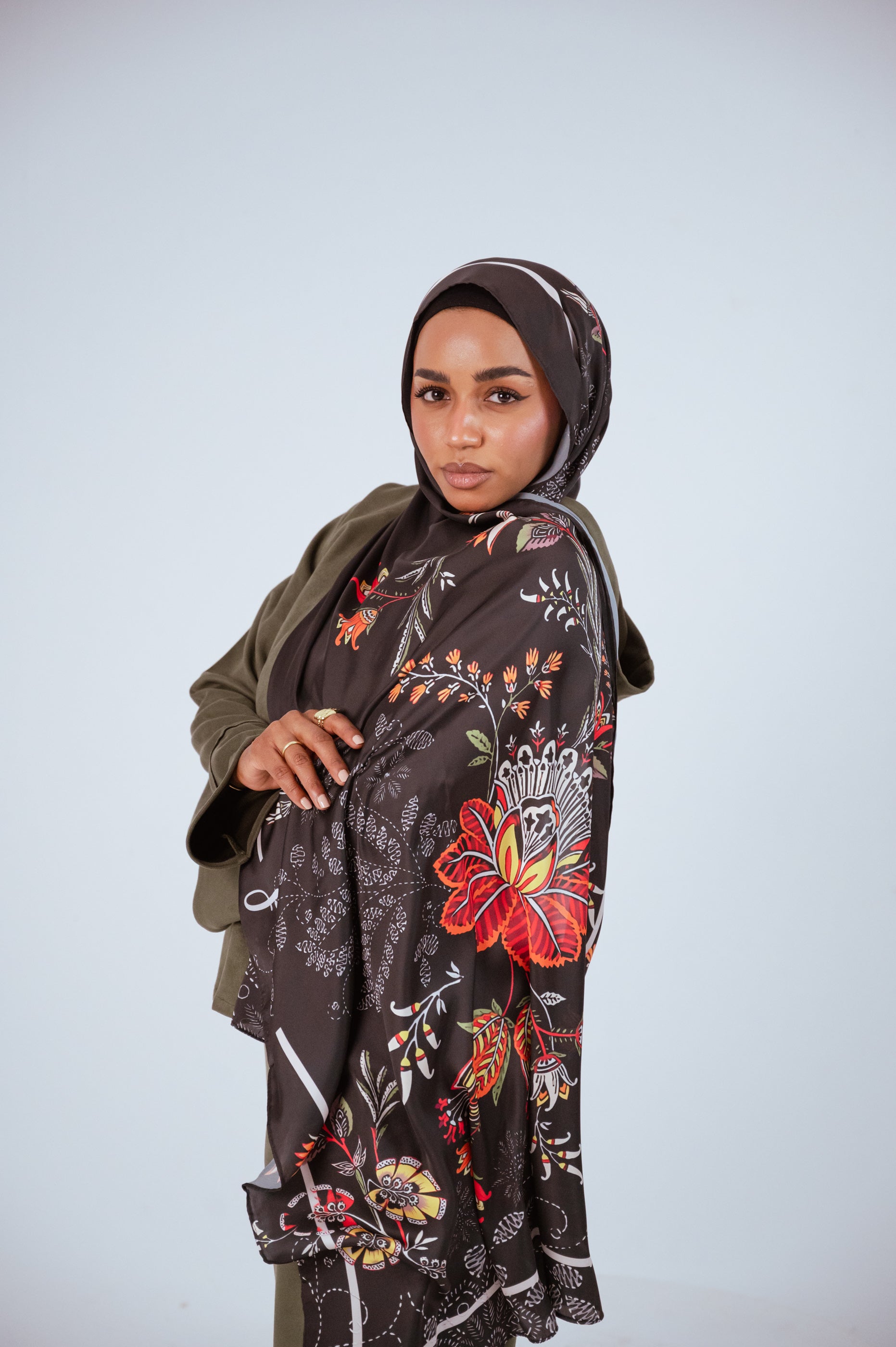 Model wearing the Scarlet of Granada satin hijab, showcasing the vibrant red floral motif on deep brown satin.