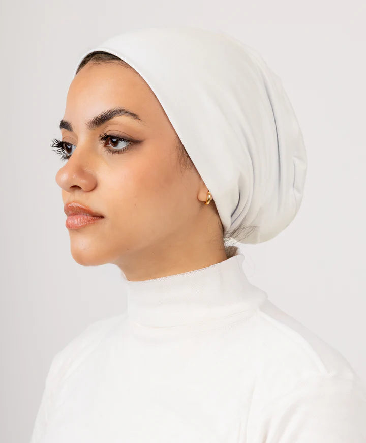 Model wearing Jaida Off-White No Thread Underscarf (undercap), side profile, clean no-thread look for a polished hijab base.