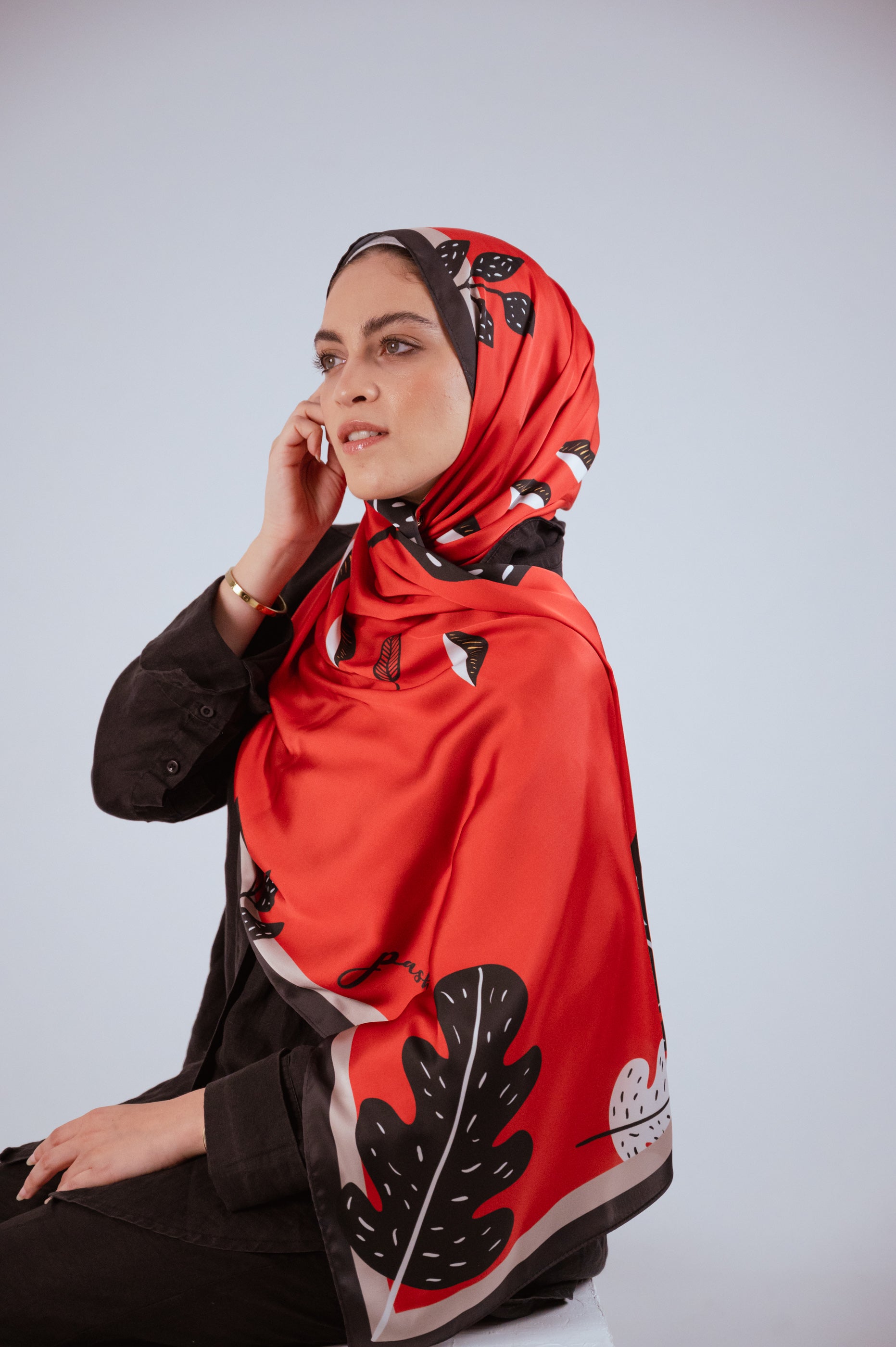 Closeup seated pose showcasing the Bold Botanica satin hijab with a soft glam expression and smooth drape.