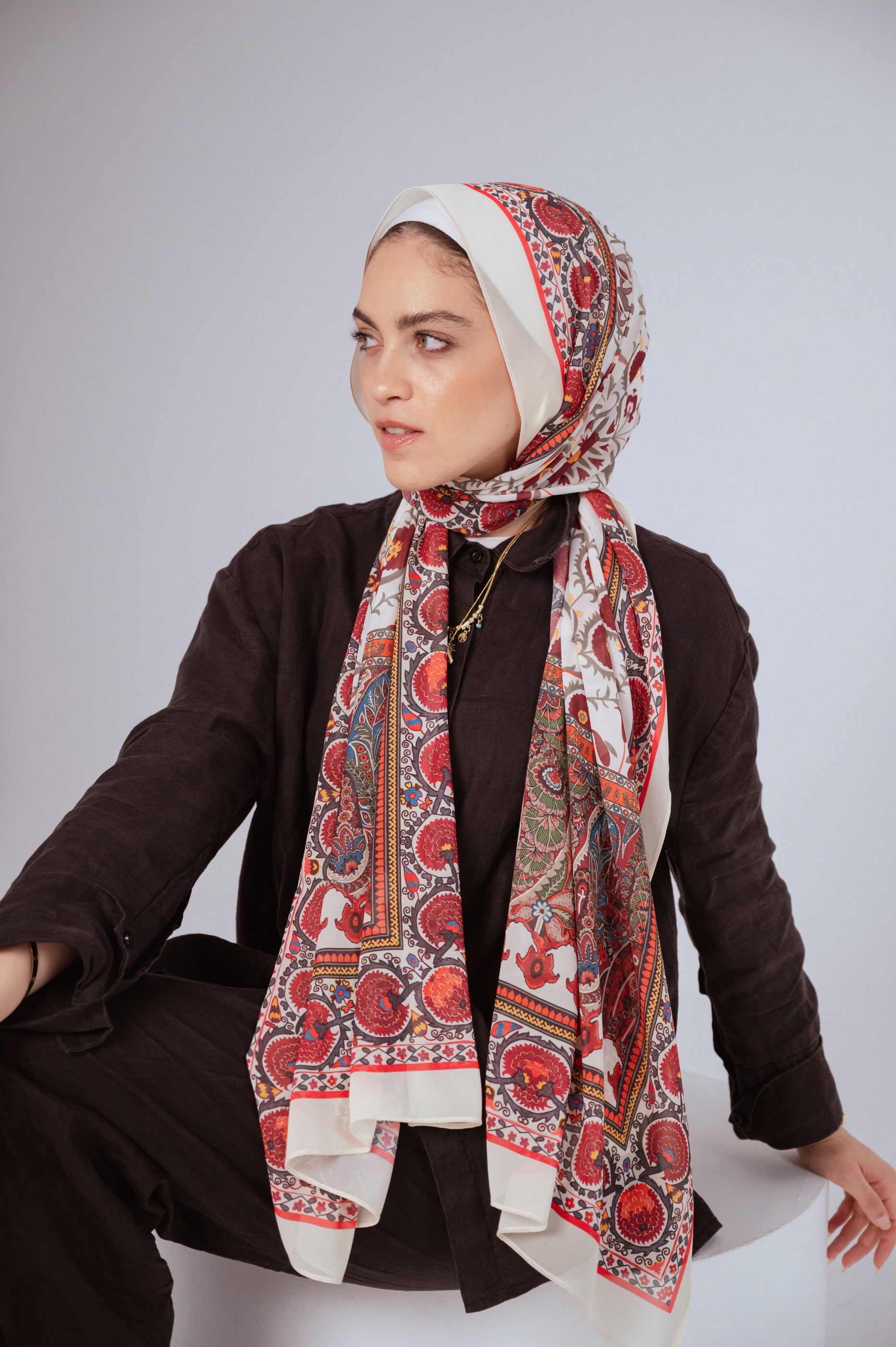Close-up of model wearing Cairo Nights luxury chiffon hijab with red and cream tapestry print.