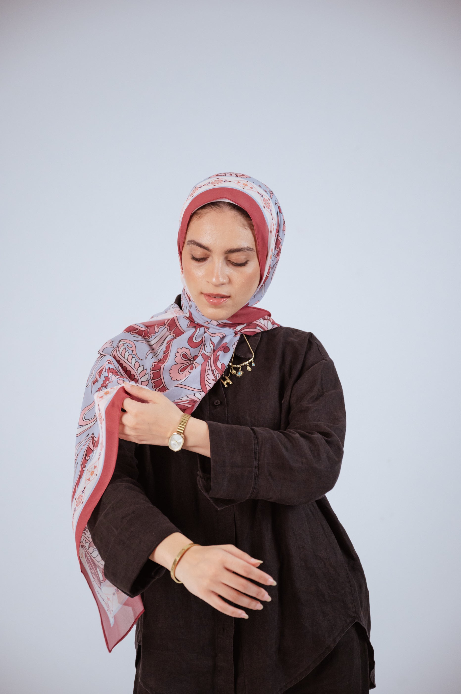 Model wearing Alhambra Bloom luxury chiffon hijab, soft rose and blue print, styled in natural light.