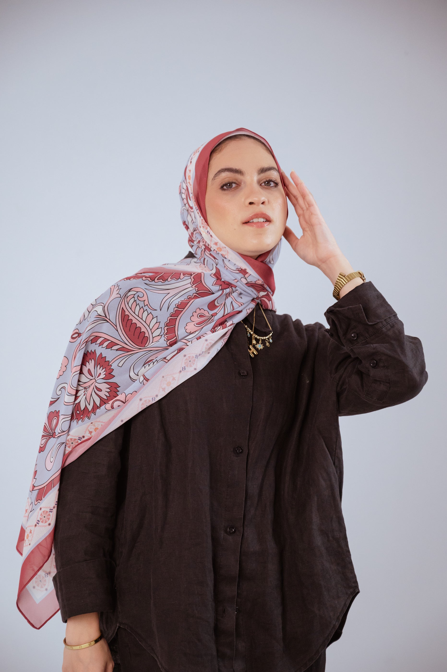 Model wearing Alhambra Bloom luxury chiffon hijab, soft rose and blue print, styled in natural light.