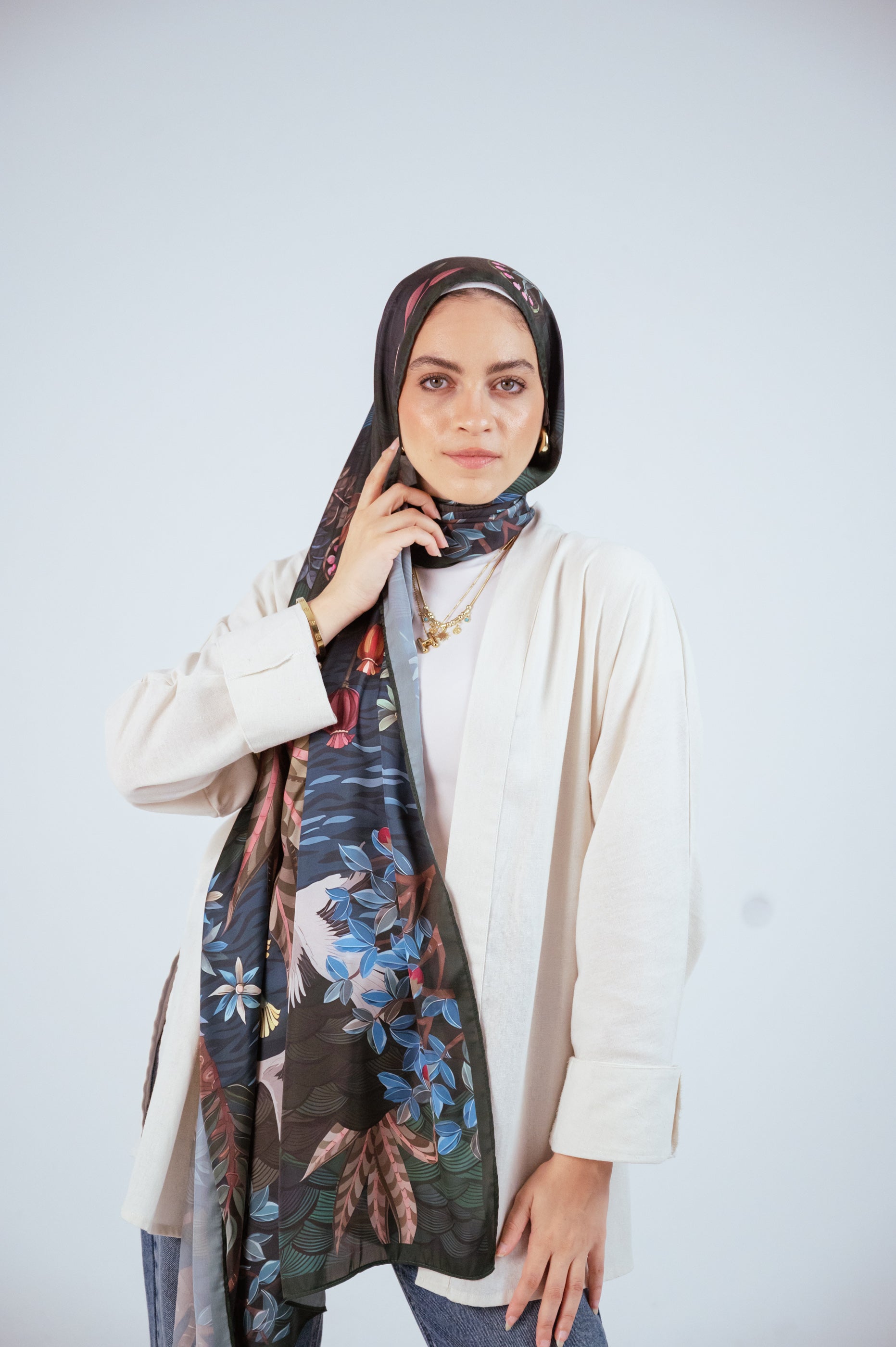 Model touching hijab, showcasing detailed print and sheen.