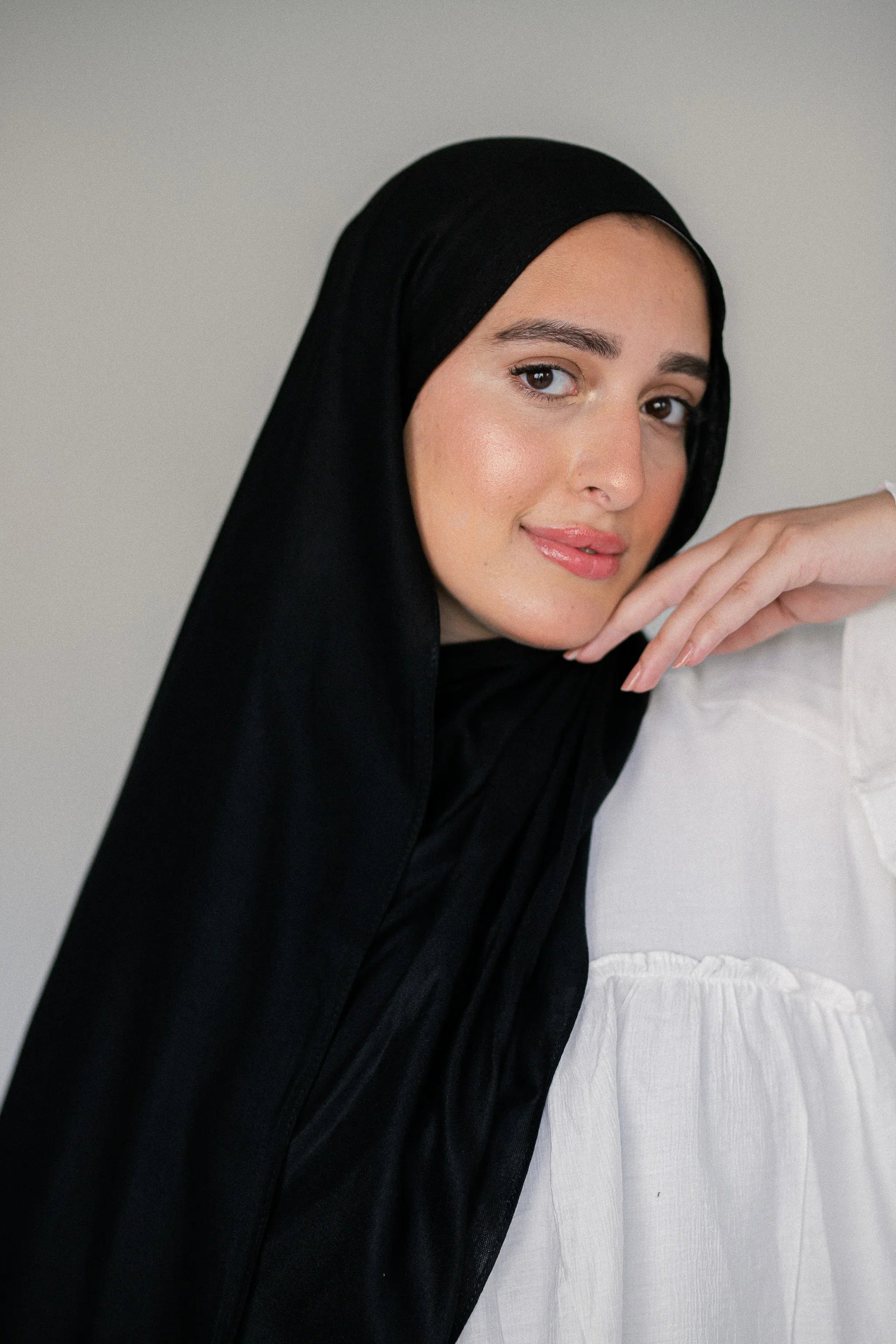 Woman wearing Jaida’s Noir Éclipse black modal cotton hijab styled simply with a white blouse, showing elegant drape and natural texture.