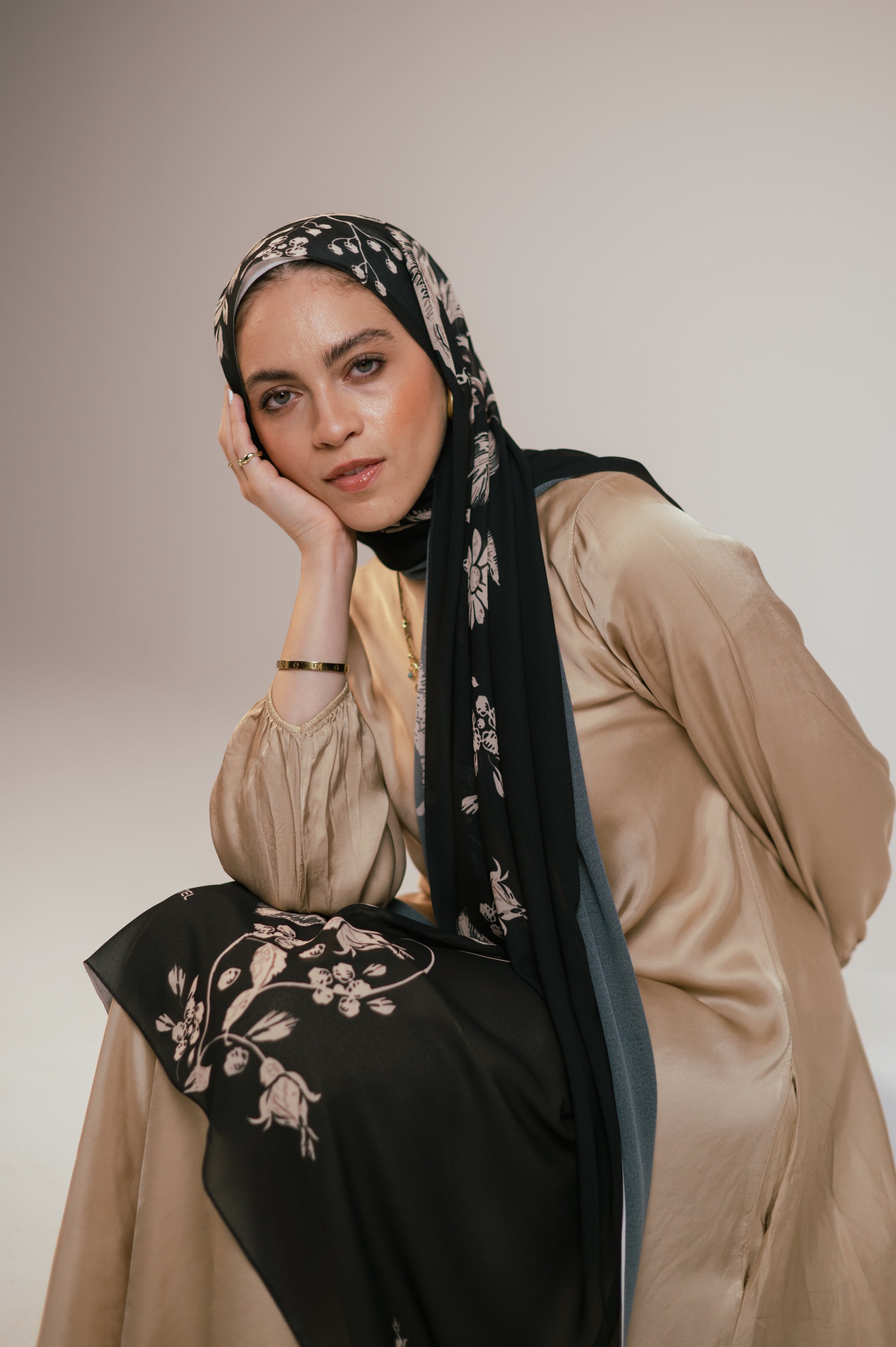 Close-up portrait of model wearing Petal Shadows chiffon hijab, highlighting the beige-on-black floral print.
