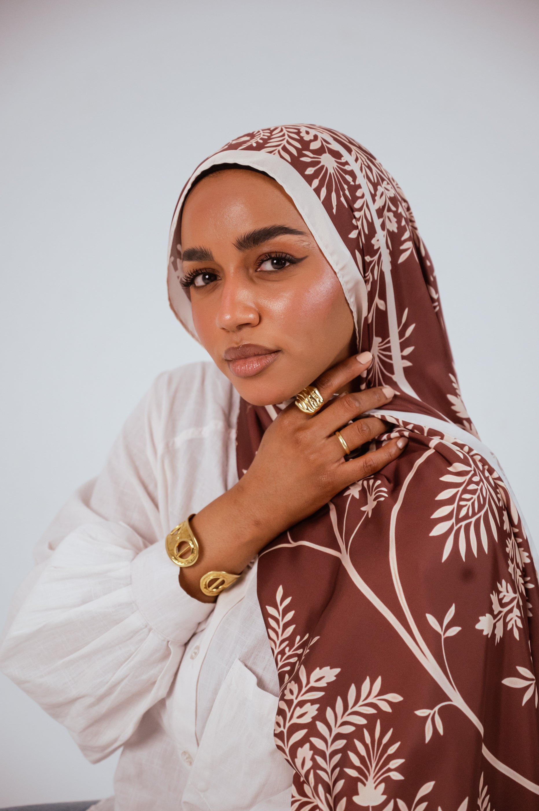 Model in Rose of Petra satin hijab looking downward, showcasing warm rosewood tones