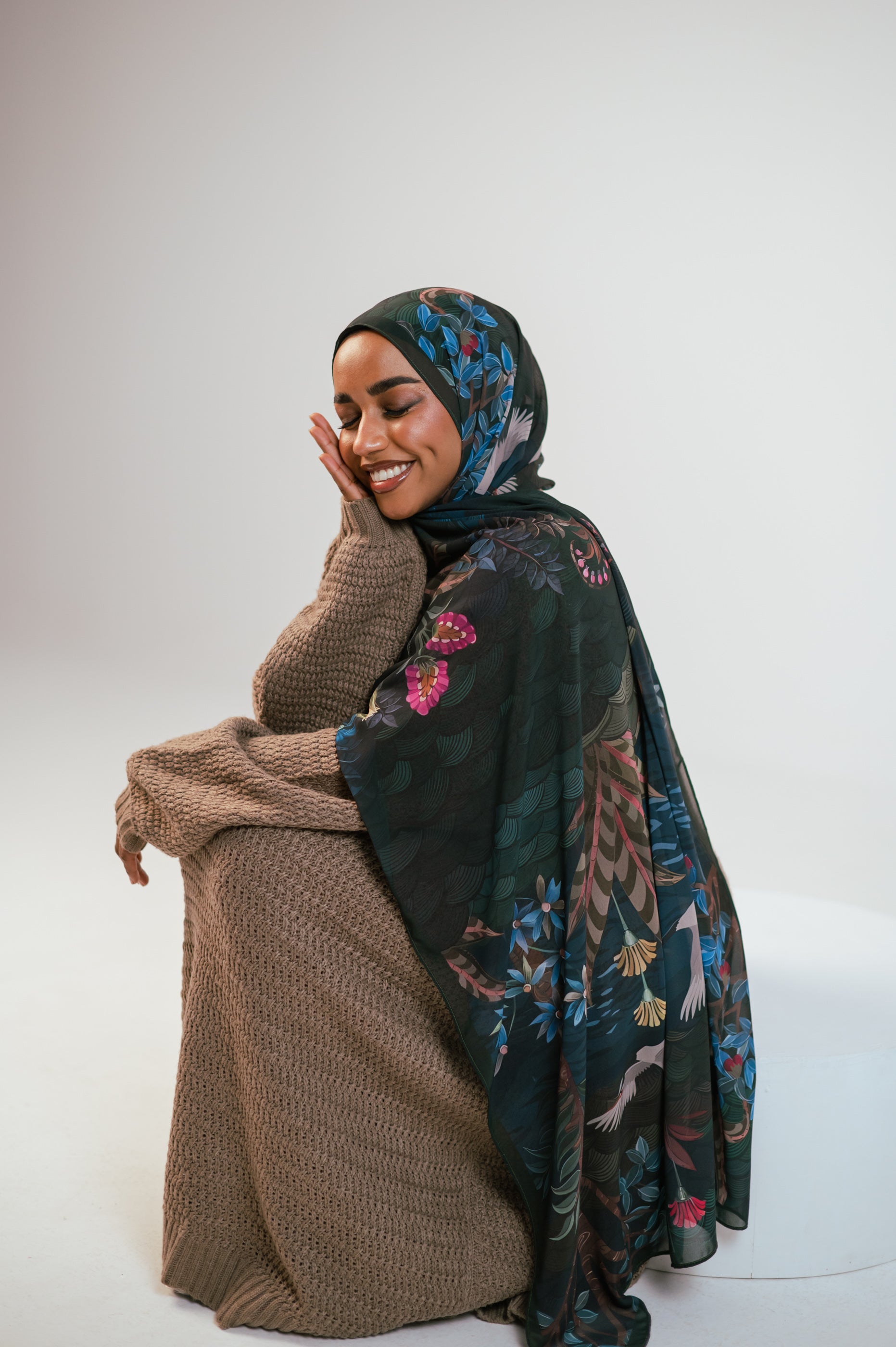Model looking down while wearing Secret Garden Luxury Chiffon Hijab, highlighting the flowing drape and floral artwork.