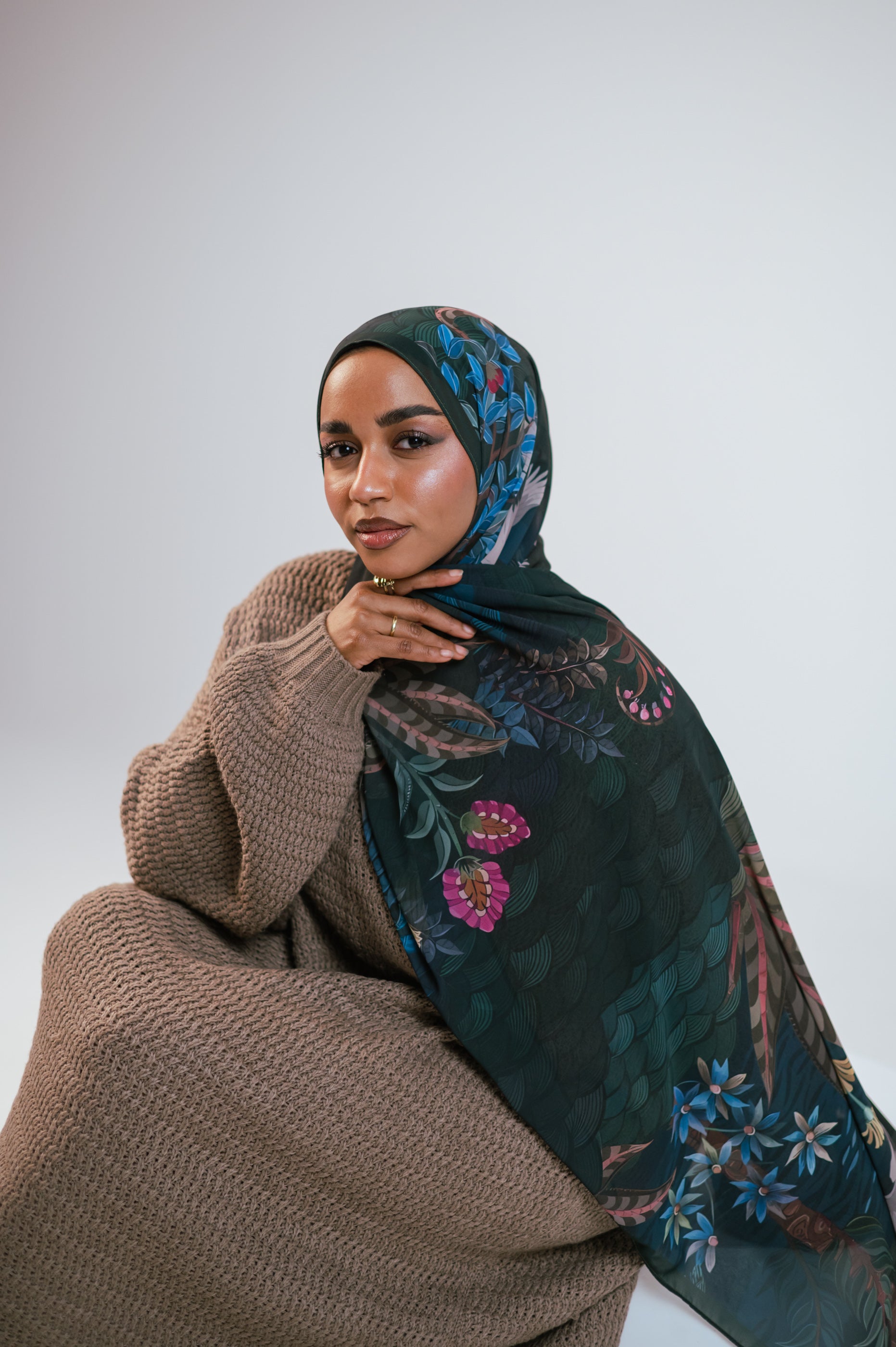 Side profile seated shot of model wearing Secret Garden Luxury Chiffon Hijab with botanical artwork.