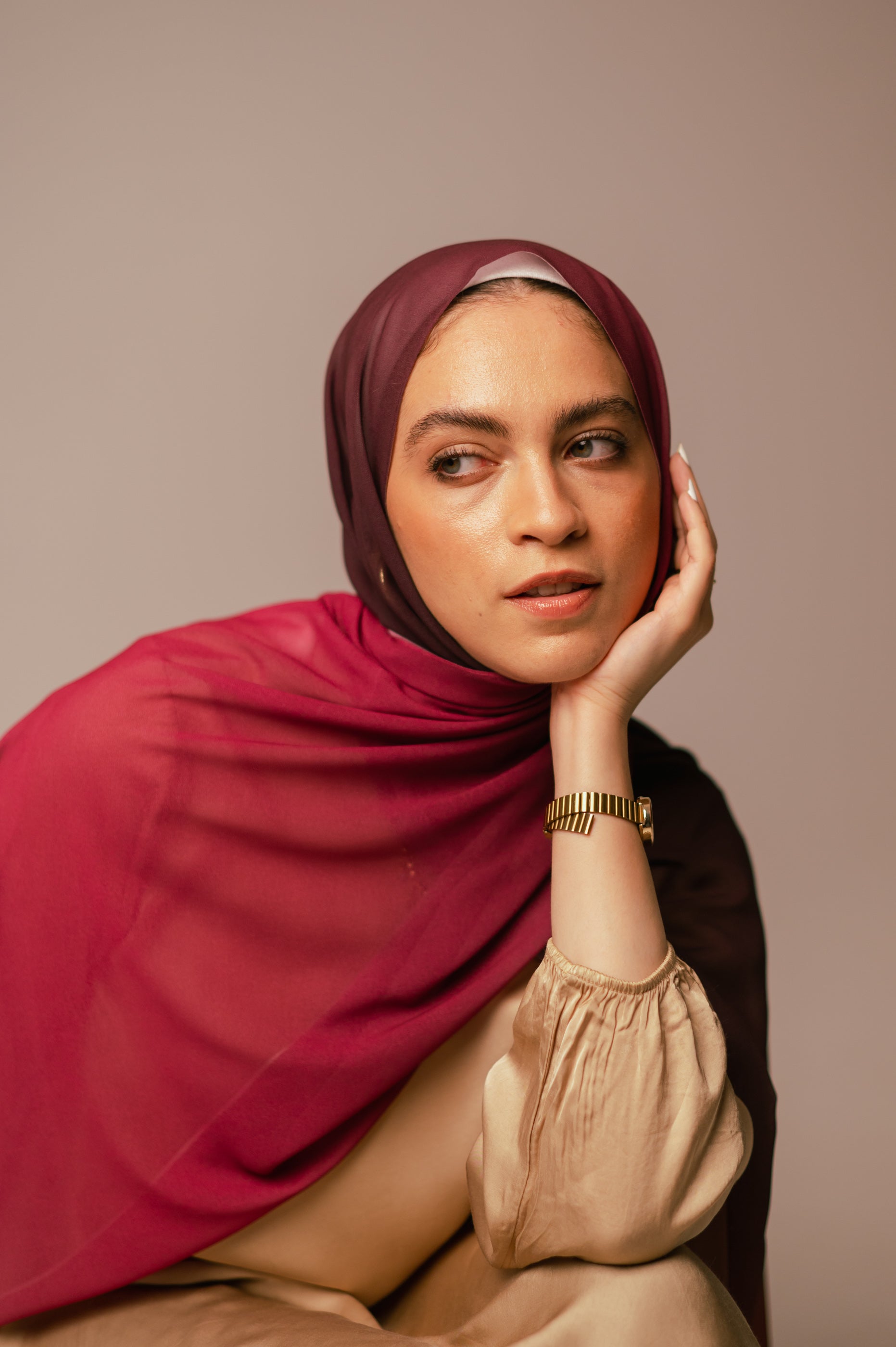Model posing with hand on face, highlighting the sheer lightweight texture of the Wisteria Sunset chiffon hijab.