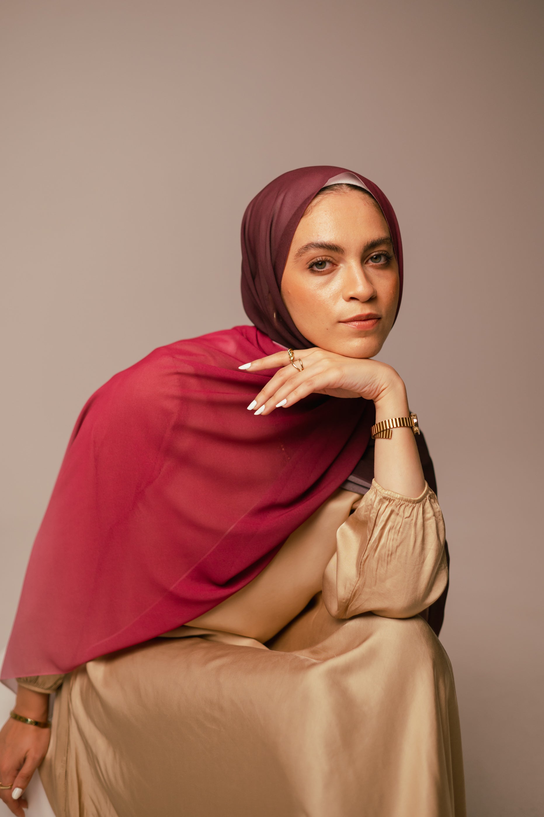Model resting chin on hand while wearing the Wisteria Sunset chiffon hijab, showing the soft drape across the shoulder.