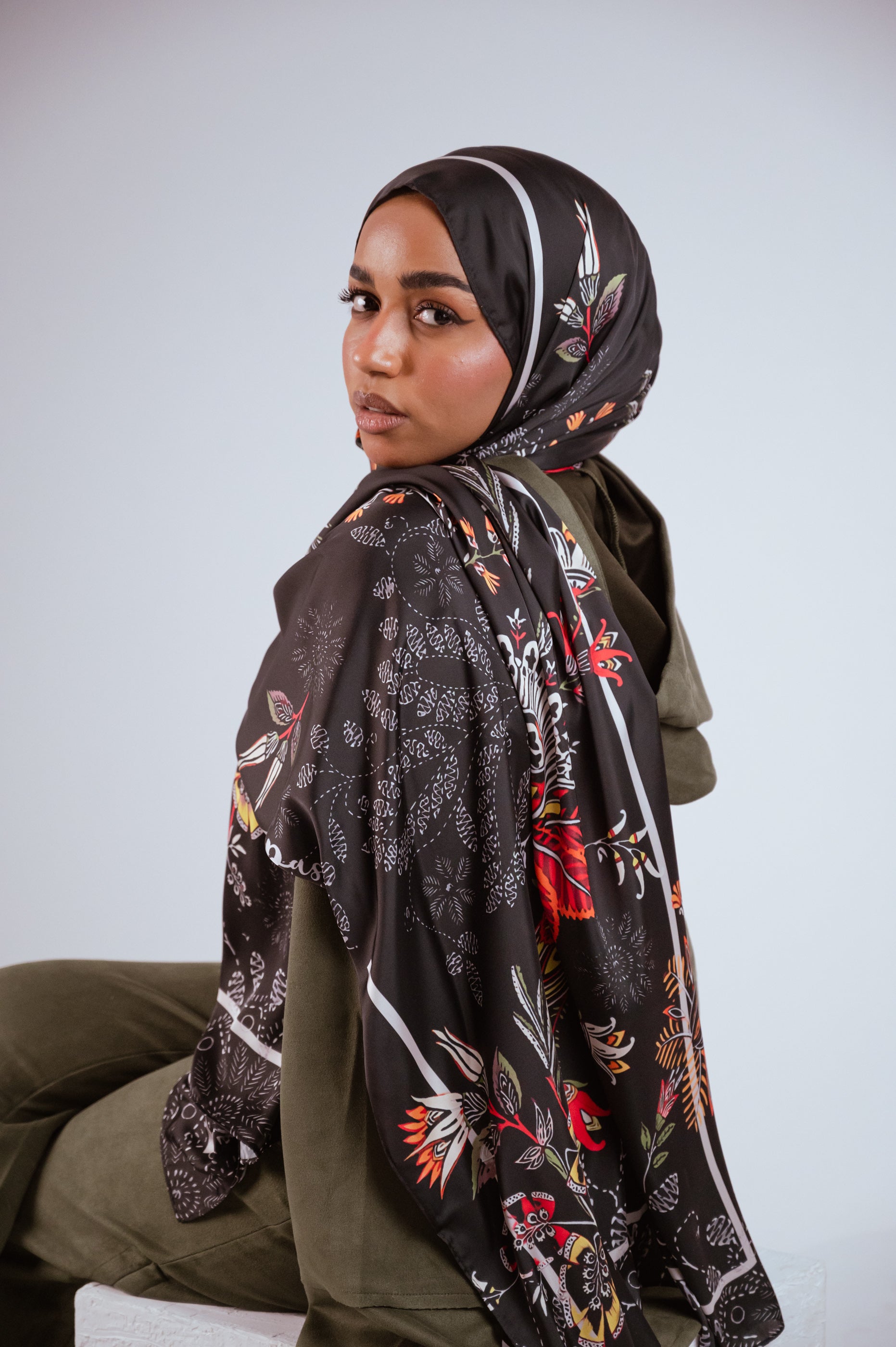 Detailed shot of the Scarlet of Granada satin hijab draped over the model’s shoulder, showing the bold statement floral design.