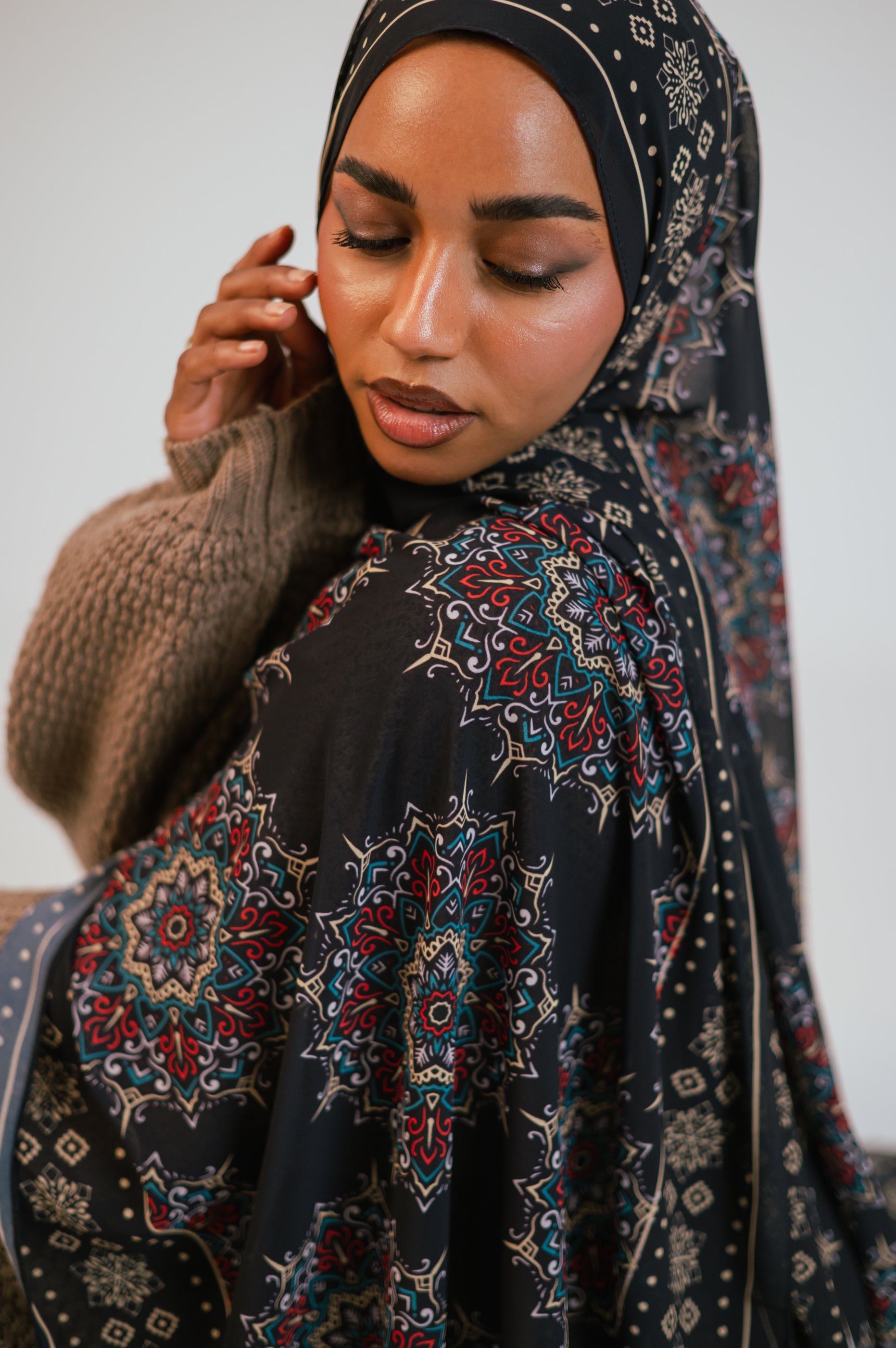 Seated three-quarter shot of the Andalusia Luxury Chiffon Hijab, highlighting the border details and rich colour palette.