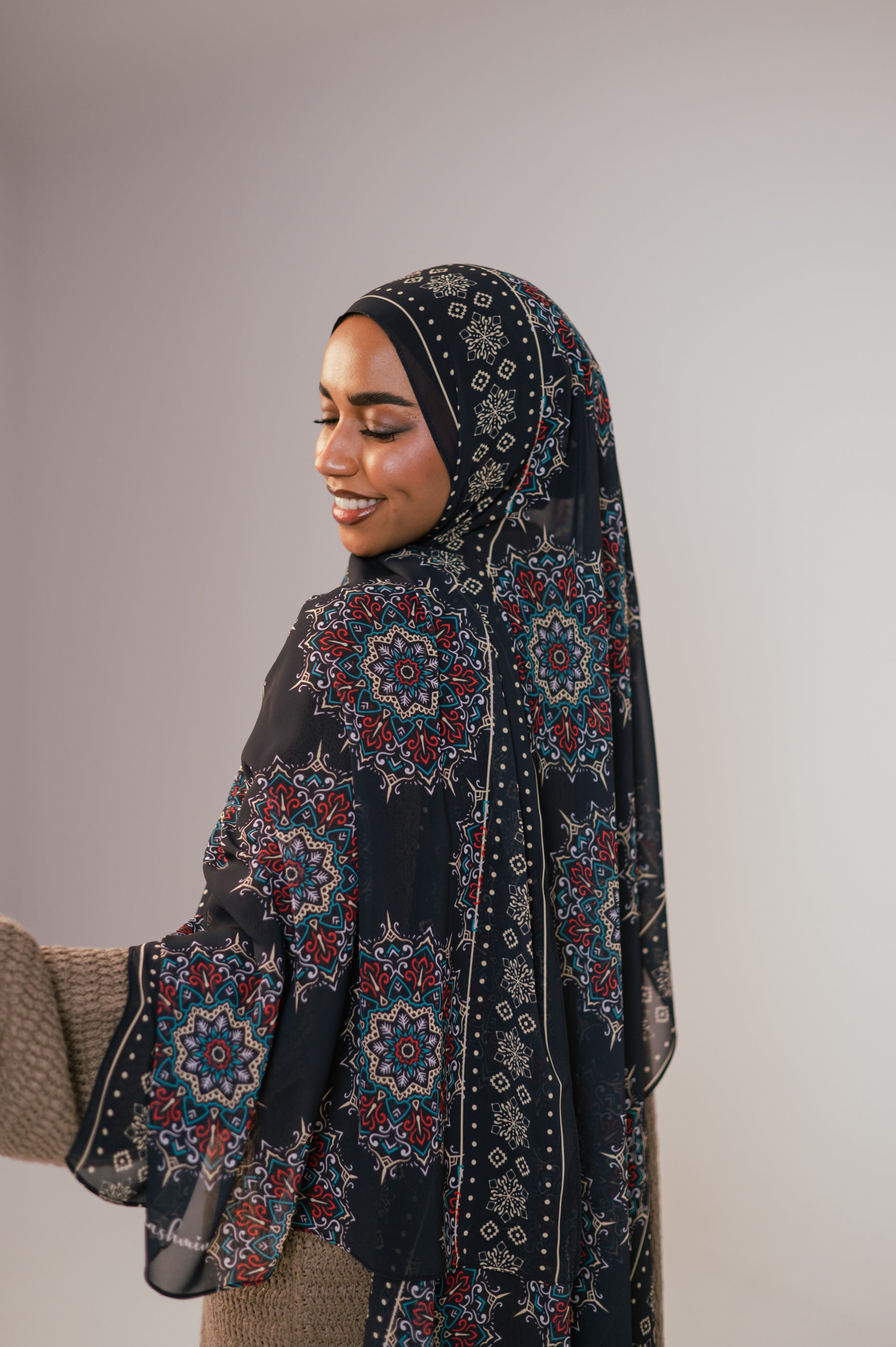 Model smiling softly while wearing the Andalusia Luxury Chiffon Hijab, showing the delicate border design and fluid movement of the fabric.