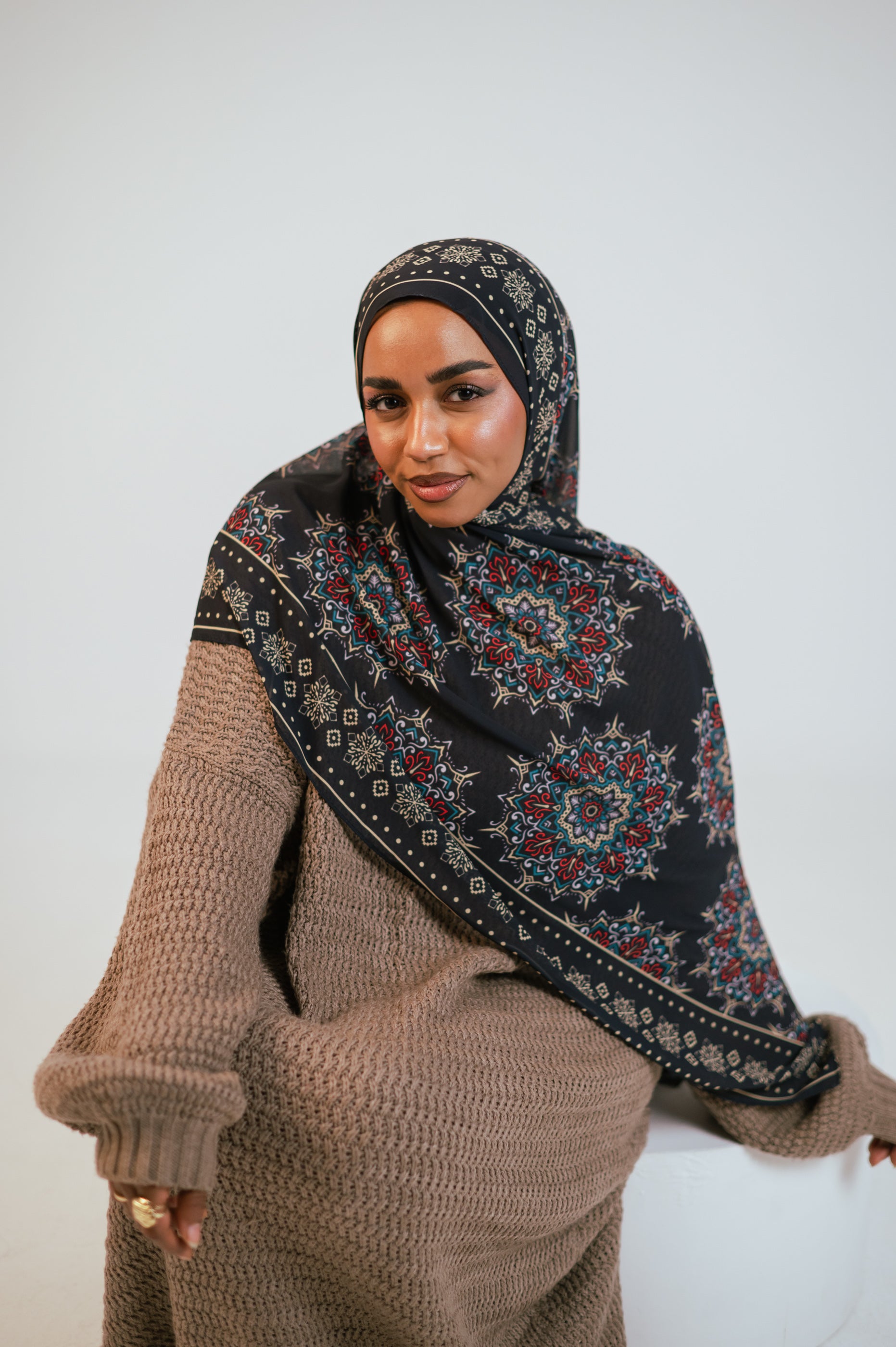 Full-body sitting pose with the model wearing the Andalusia Luxury Chiffon Hijab, showcasing the complete look and effortless styling.