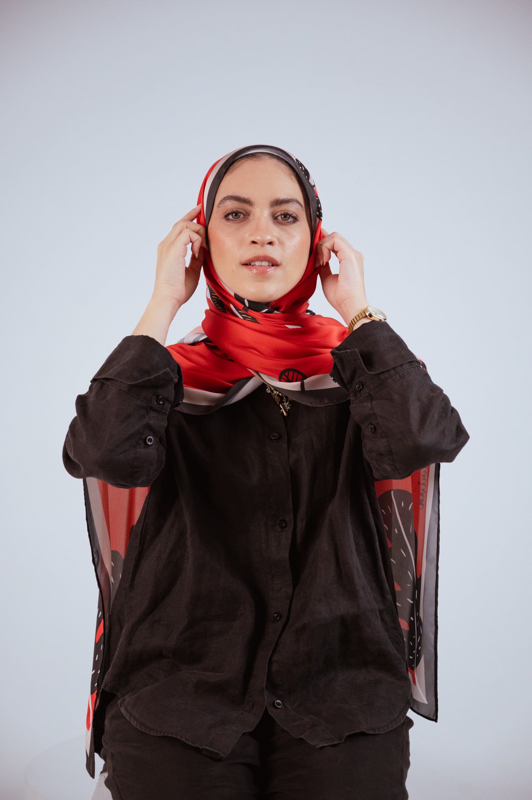 Model adjusting the Bold Botanica satin hijab, showing the versatility of the wrap and the bold botanical artwork.