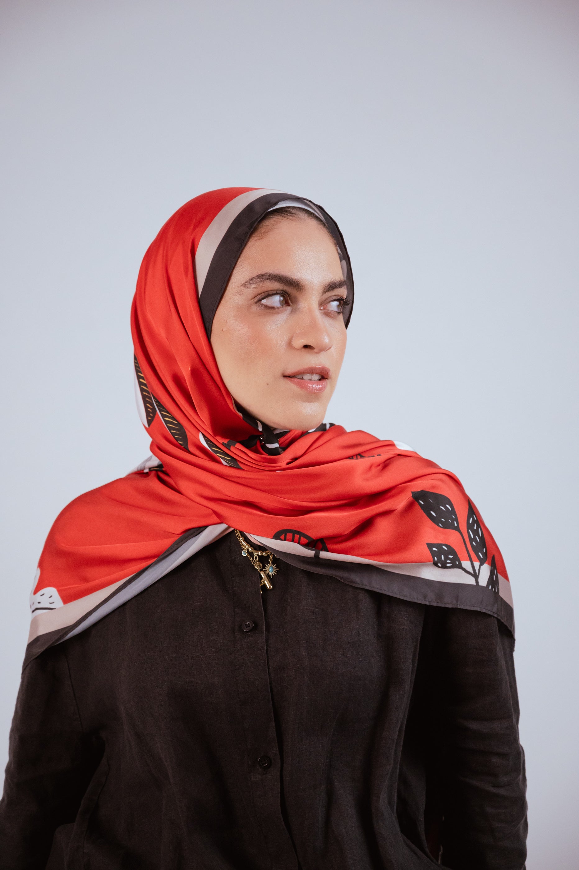 Model wearing the Bold Botanica red satin hijab styled over the shoulders, showcasing the smooth drape and bold botanical print.