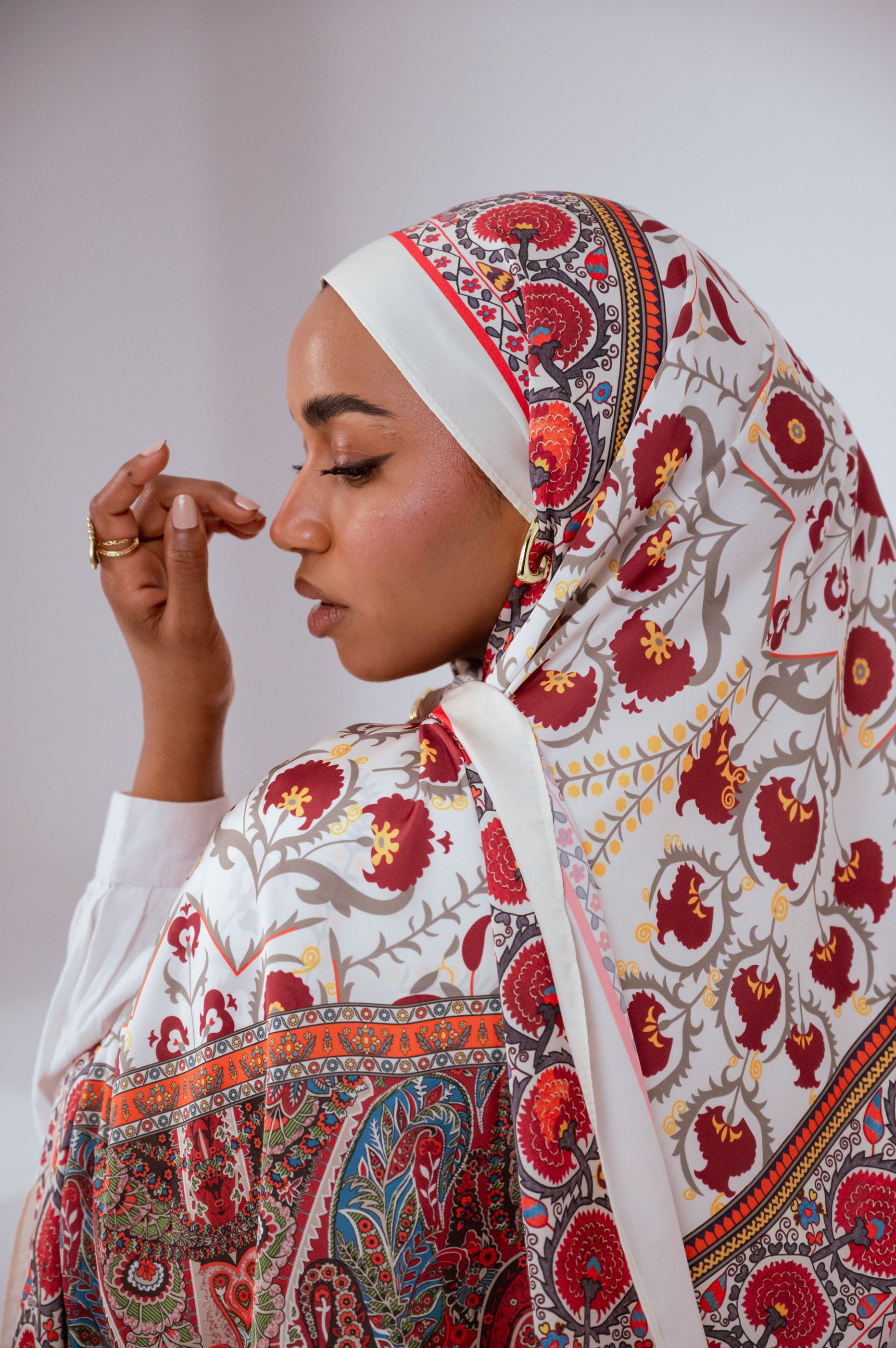Side profile of the model wearing the Cairo Nights Satin Hijab, showing the ornate border and rich Middle Eastern-inspired patterns.