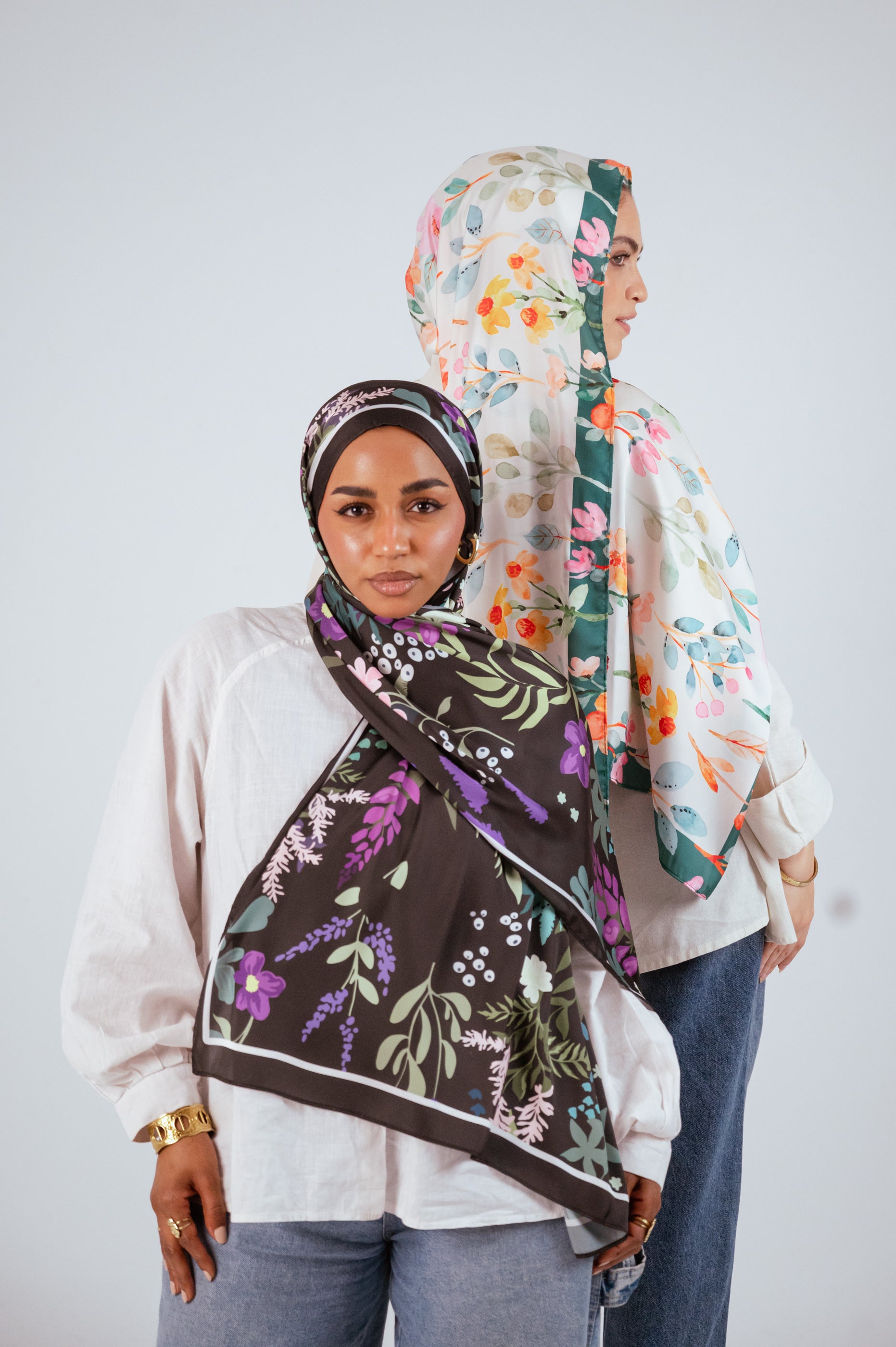 Front view of two models wearing Garden of Whispers and Blooms of Hope satin hijabs showcasing floral prints.