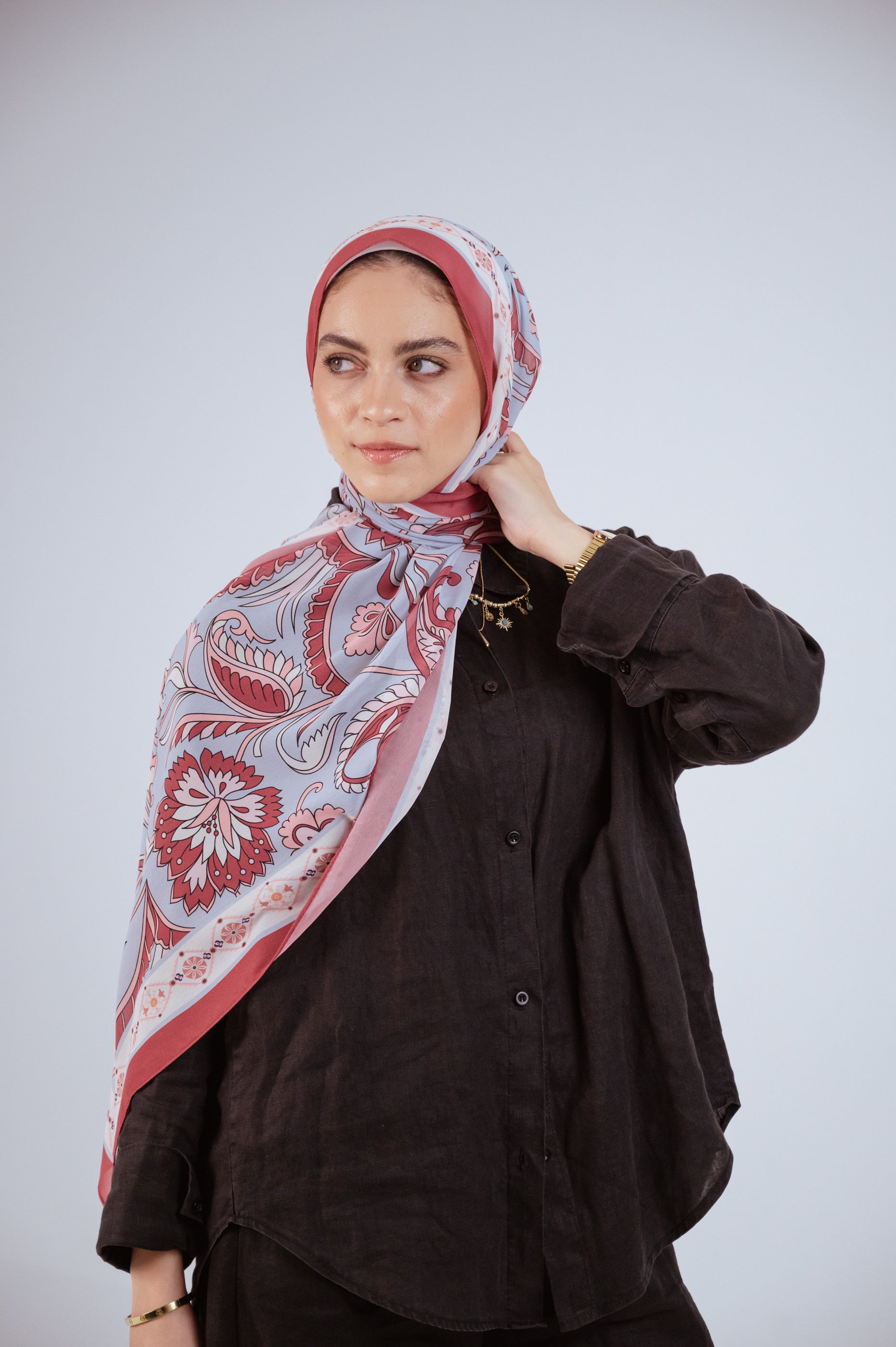 Model wearing Alhambra Bloom luxury chiffon hijab, soft rose and blue print, styled in natural light.