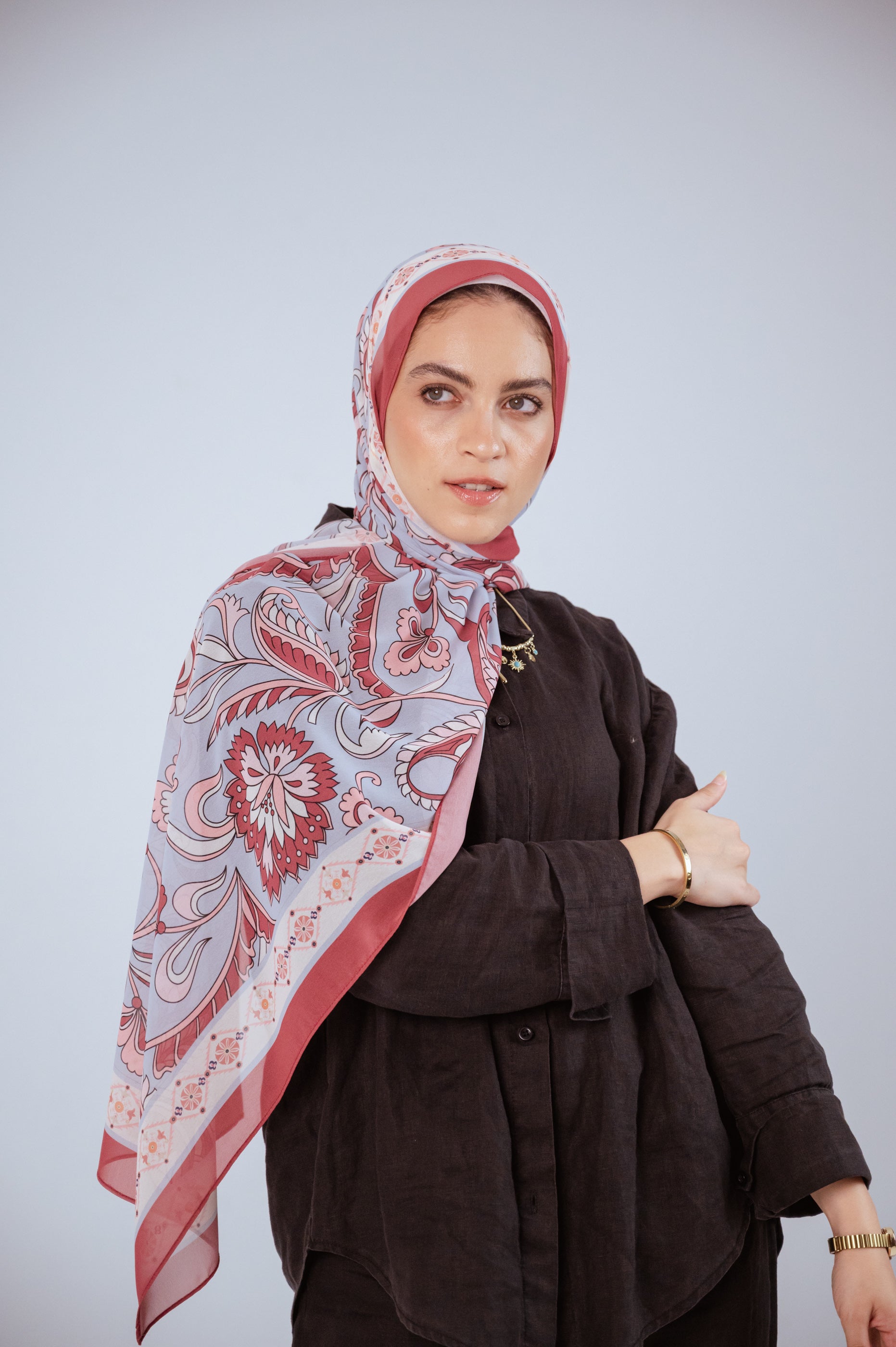 Model wearing Alhambra Bloom luxury chiffon hijab, soft rose and blue print, styled in natural light.