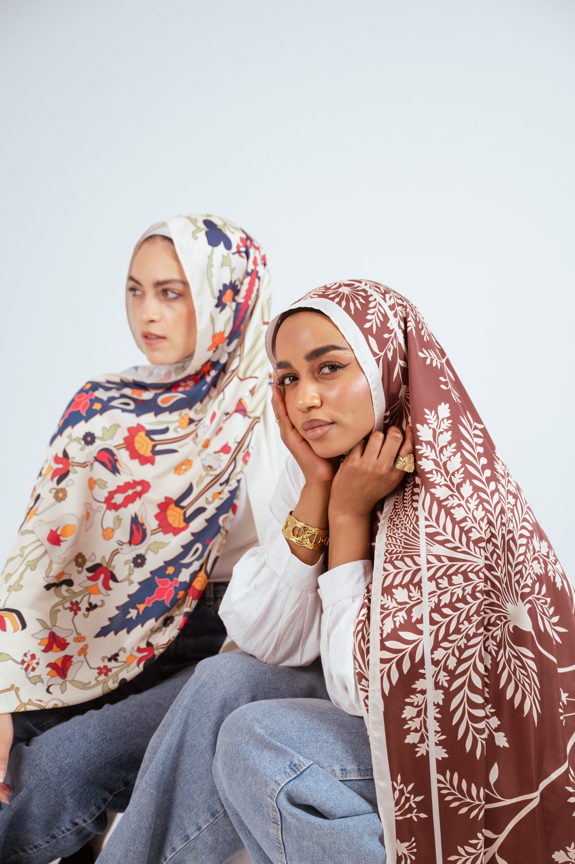 Models posed together wearing Andalus Drape Satin and Rose of Petra Satin hijabs from Jaida’s printed satin collection.