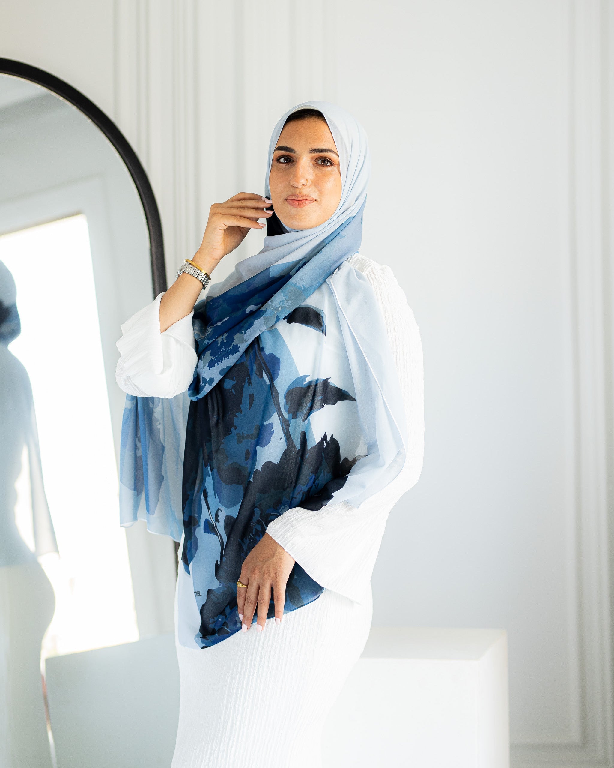 Model styling Jaida Azure Bloom chiffon hijab in a casual modest outfit, draped over white dress