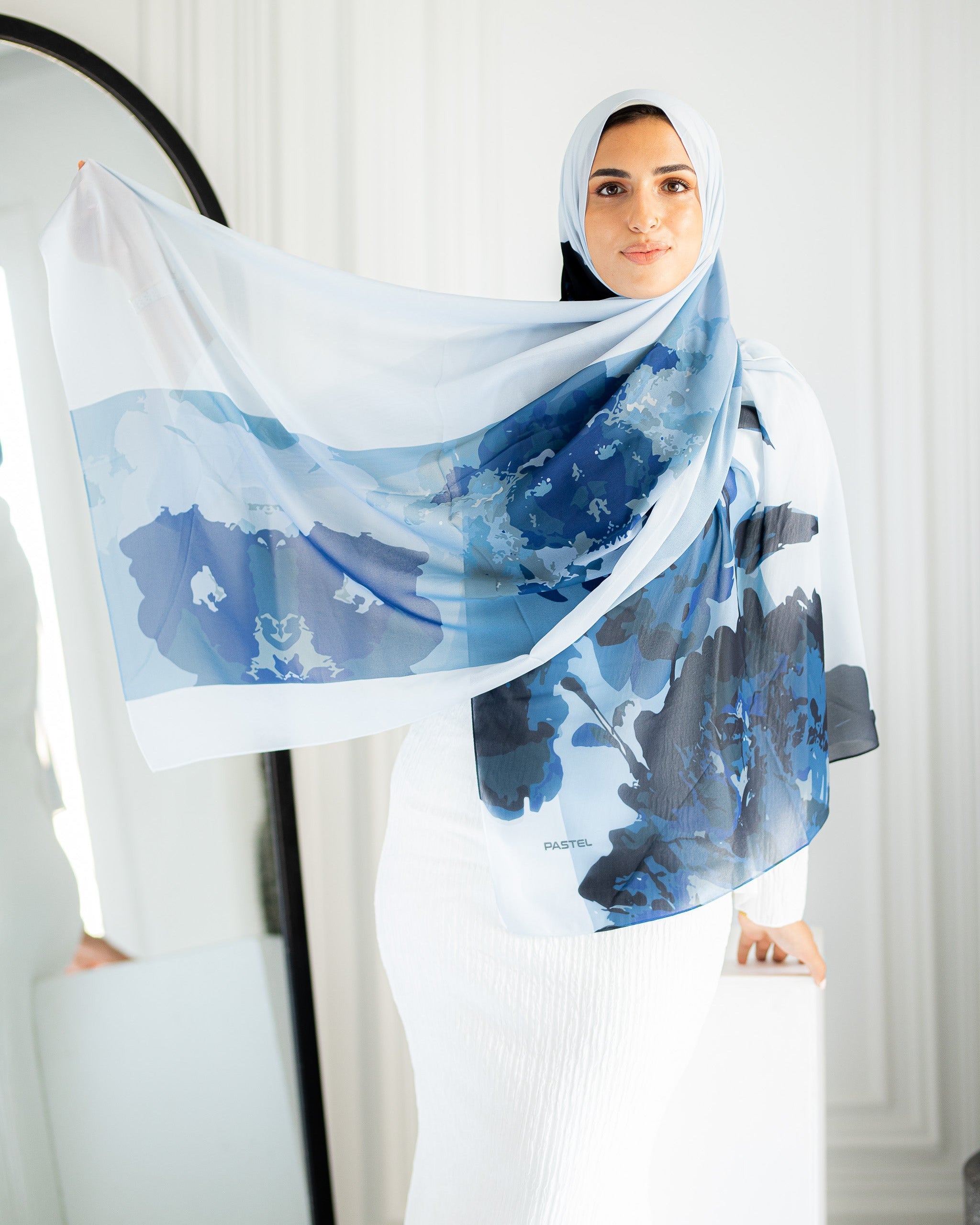Model styling Jaida Azure Bloom chiffon hijab in a casual modest outfit, draped over white dress