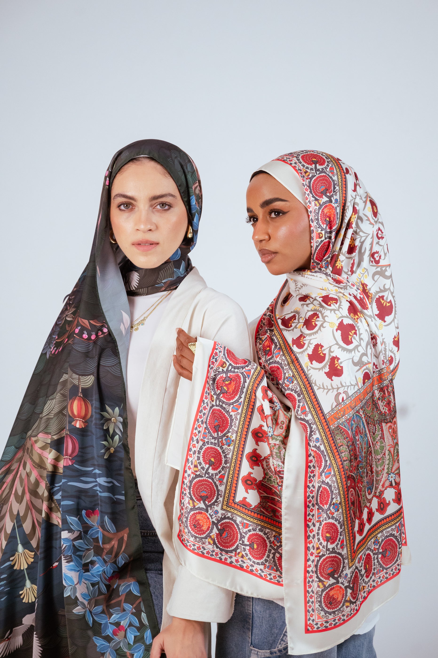 Side-by-side portrait of two models wearing Secret Garden Chiffon and Cairo Nights Satin hijabs, highlighting JAIDA’s signature artistic prints.
