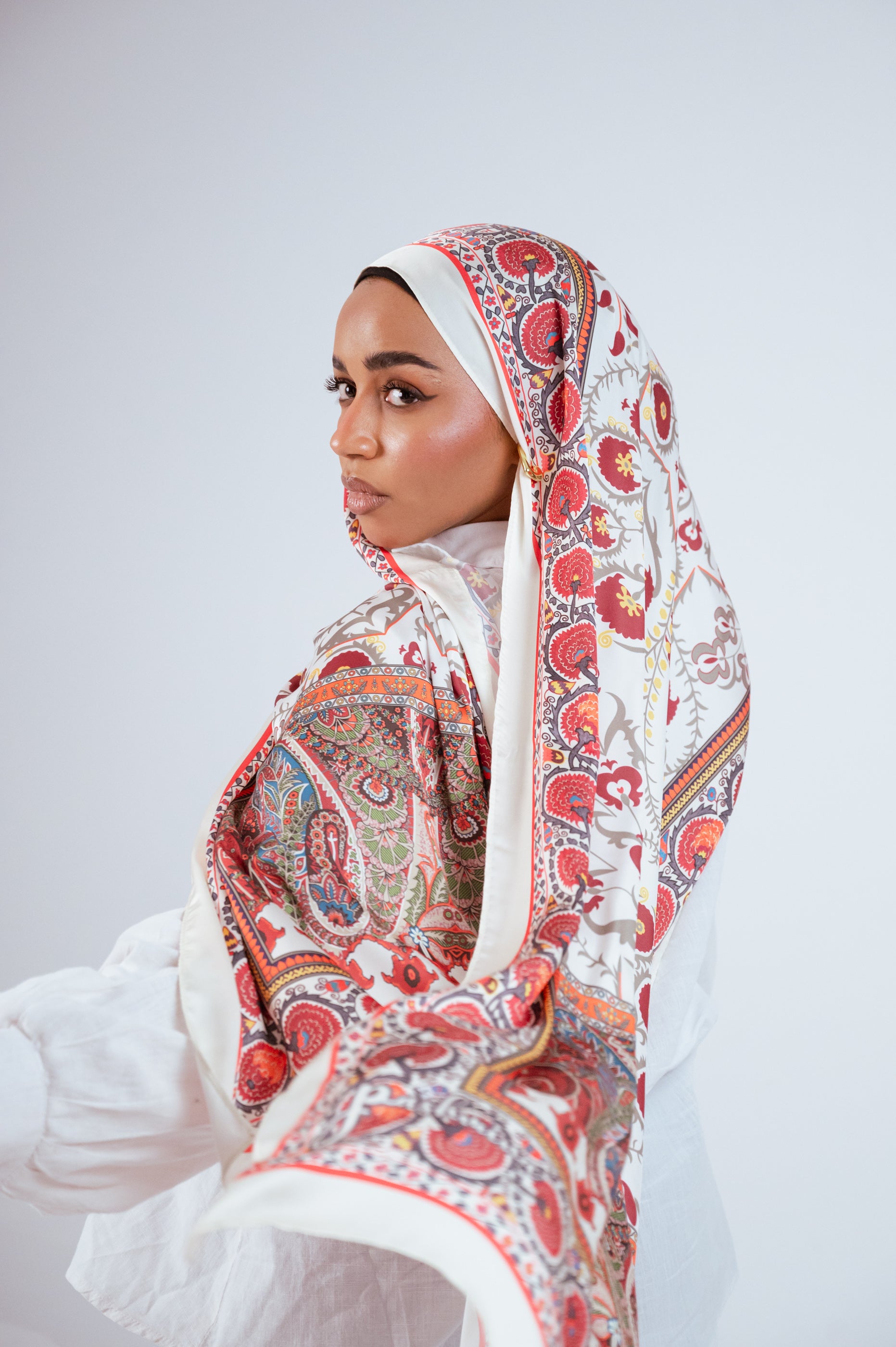 Model holding hijab near face showcasing border and print details