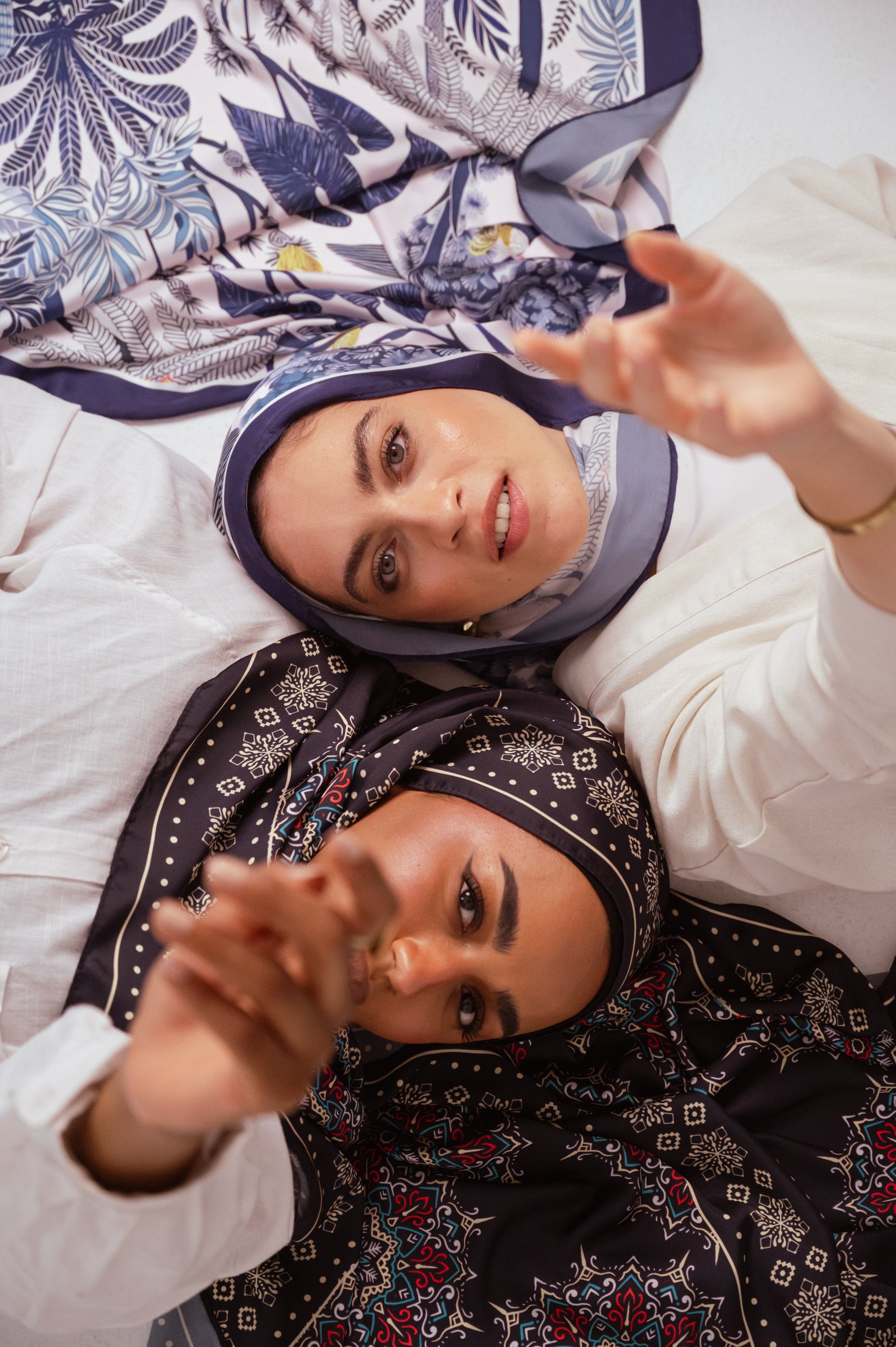 Models wearing JAIDA satin hijabs with flowing movement — Blooms of Hope and Andalusia prints.