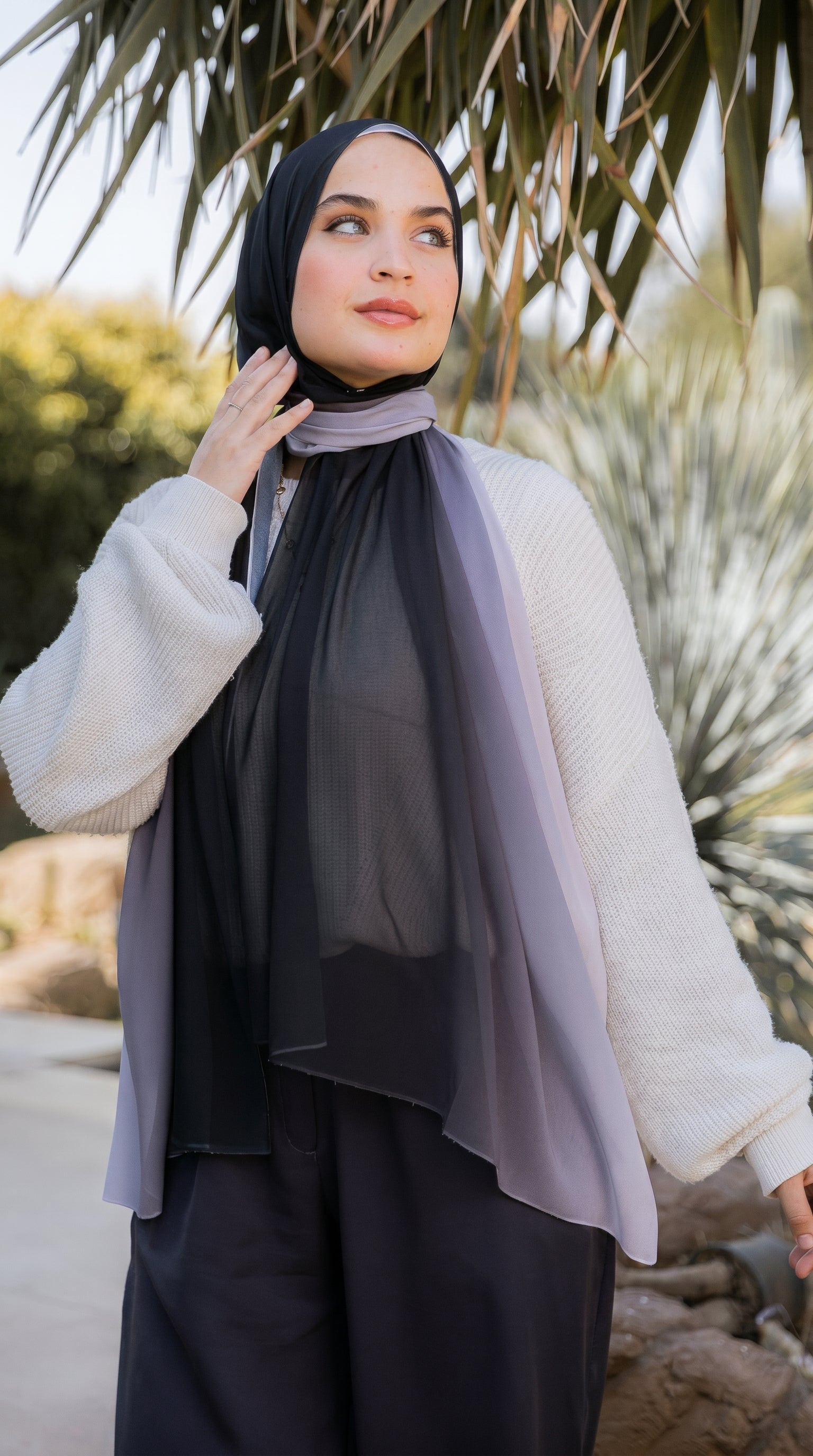 Full-length look of the Lunar Mist ombré chiffon hijab styled with a cream knit cardigan and black wide-leg trousers