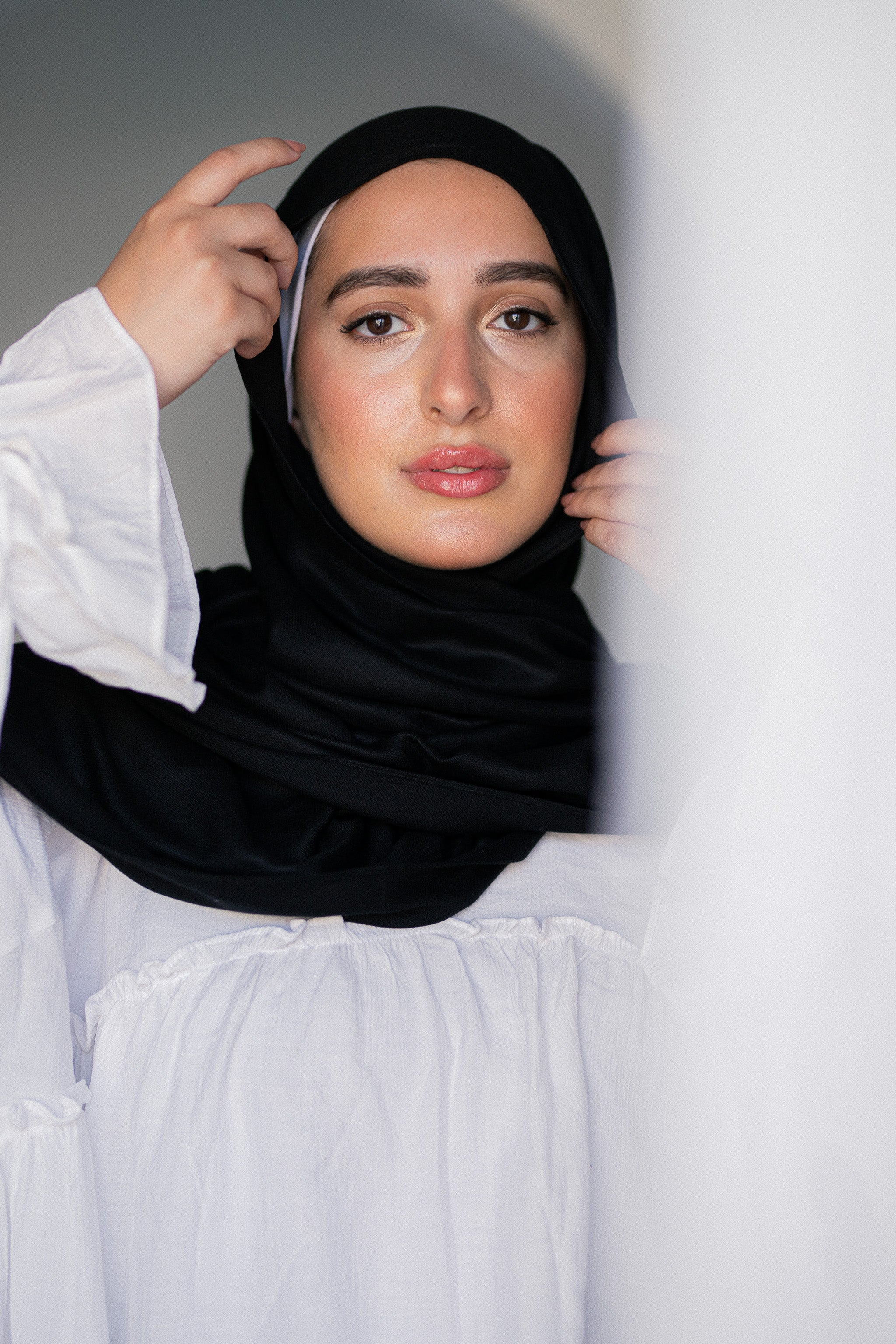 Close-up of model adjusting Noir Éclipse black hijab, highlighting its soft modal cotton texture and elegant fall.