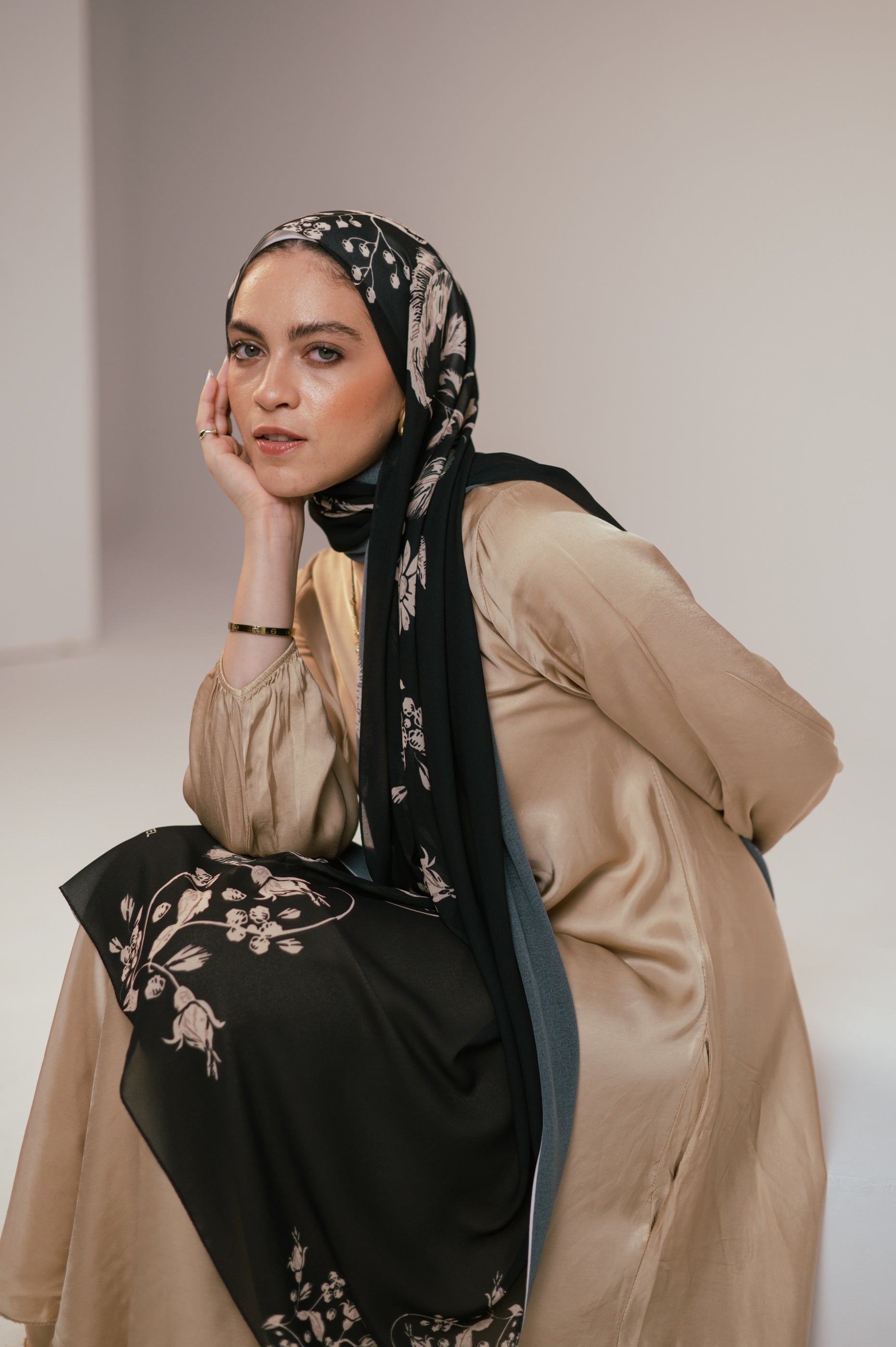 Close-up seated shot of the model wearing Petal Shadows luxury chiffon hijab, showing facial expression and pattern detail.