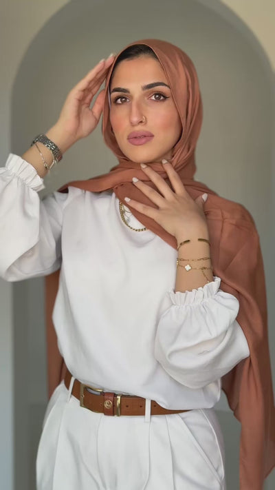 Sahara Dusk hijab moving gently in natural light, revealing golden tones and fluid drape.