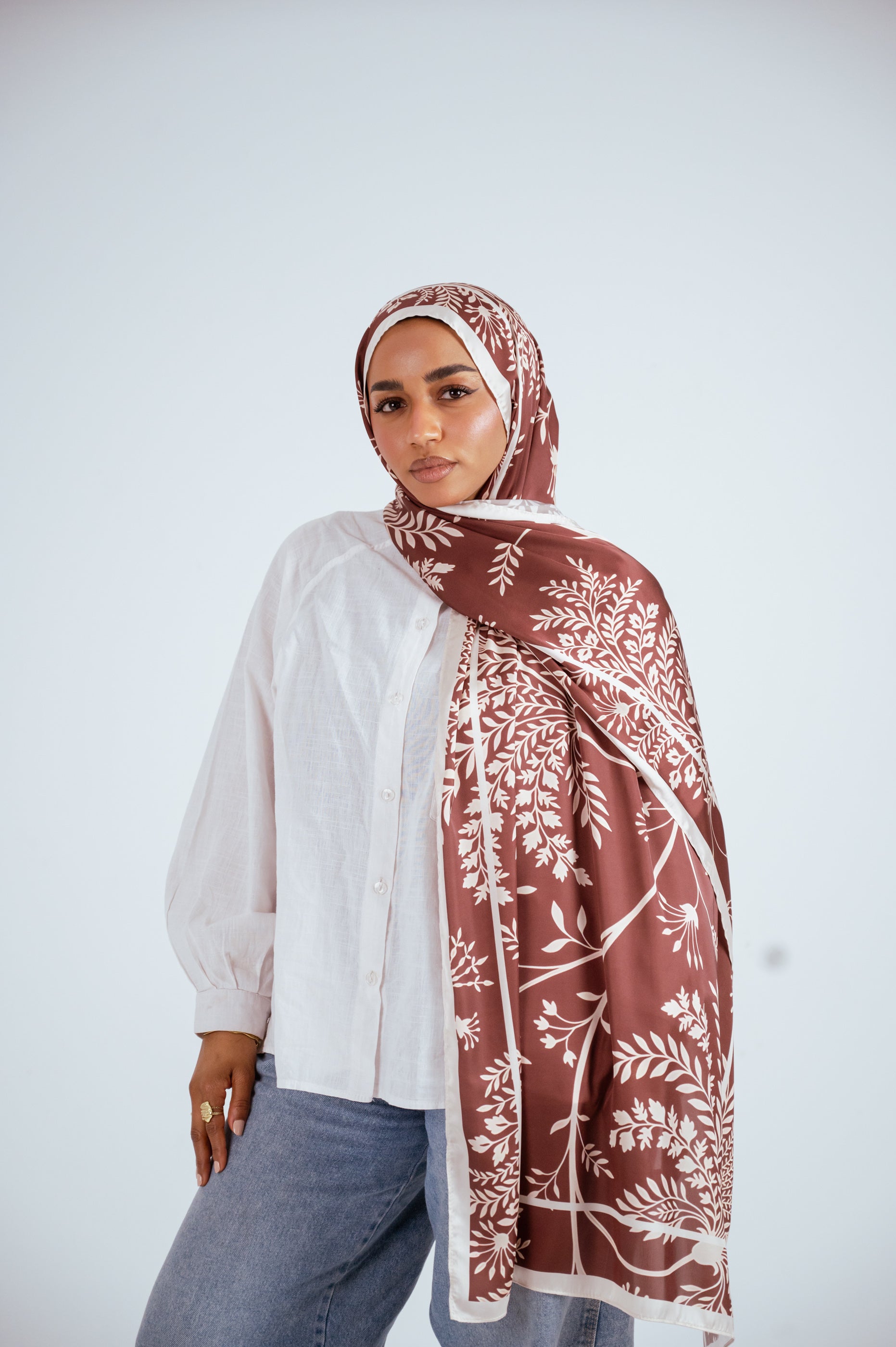 Model wearing Rose of Petra satin hijab in warm rosewood with cream botanical print, front view.