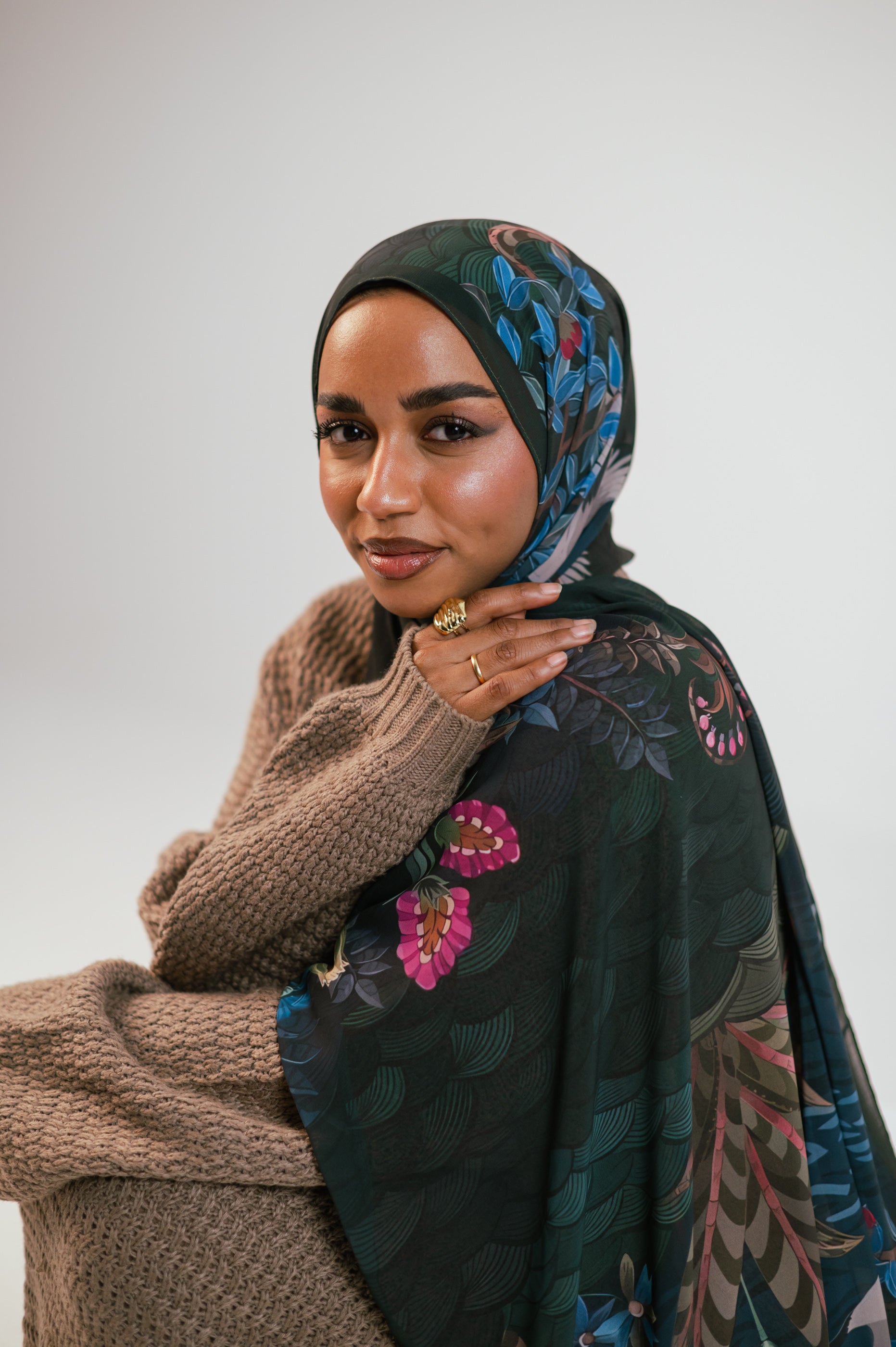 Close-up portrait of model wearing the Secret Garden Luxury Chiffon Hijab, showing deep green botanical print with pink and blue floral details.