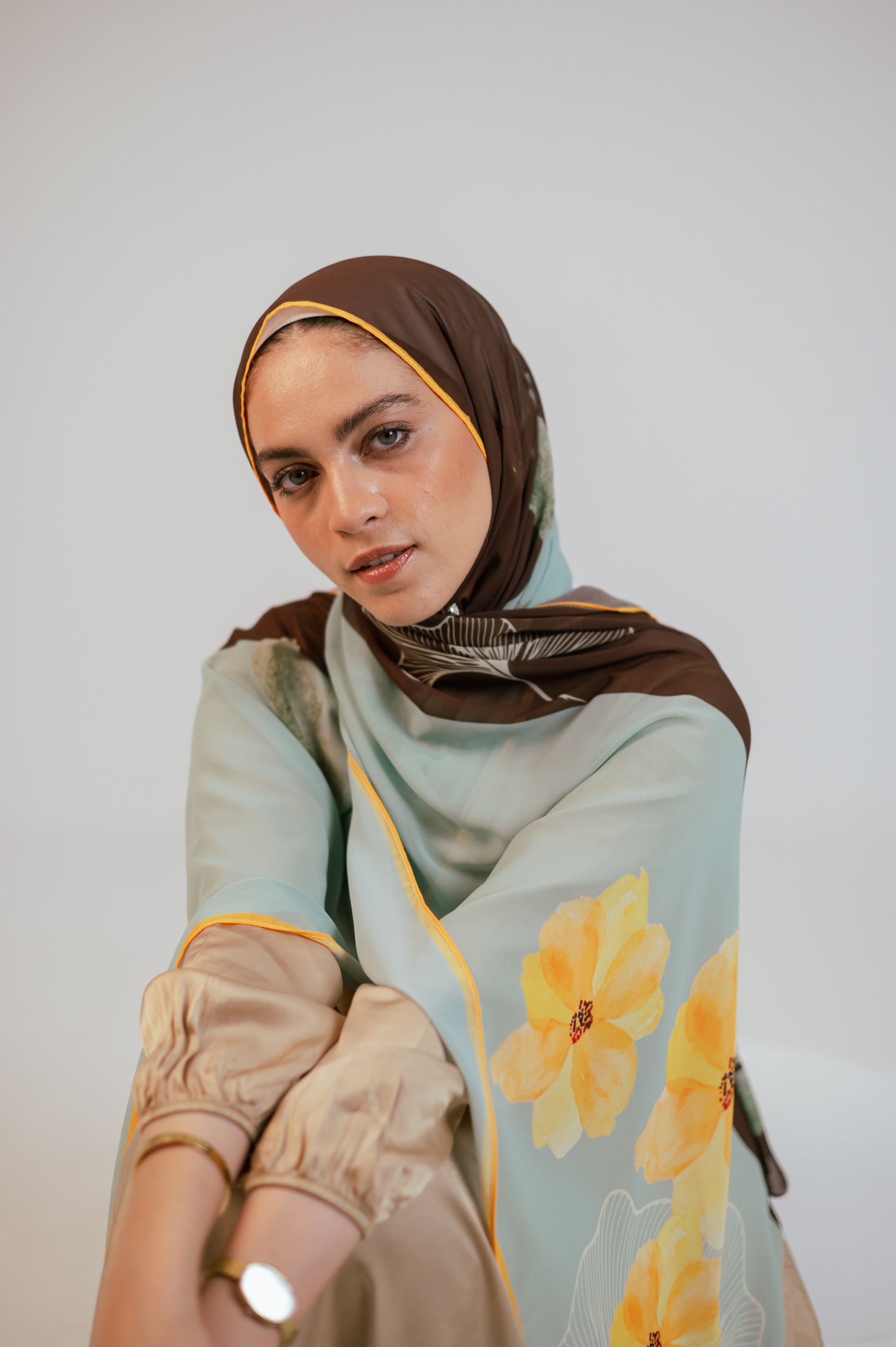 Close-up portrait of the model in the Terra Soleil chiffon hijab, emphasizing the smooth brown cap and florals along the shoulder.