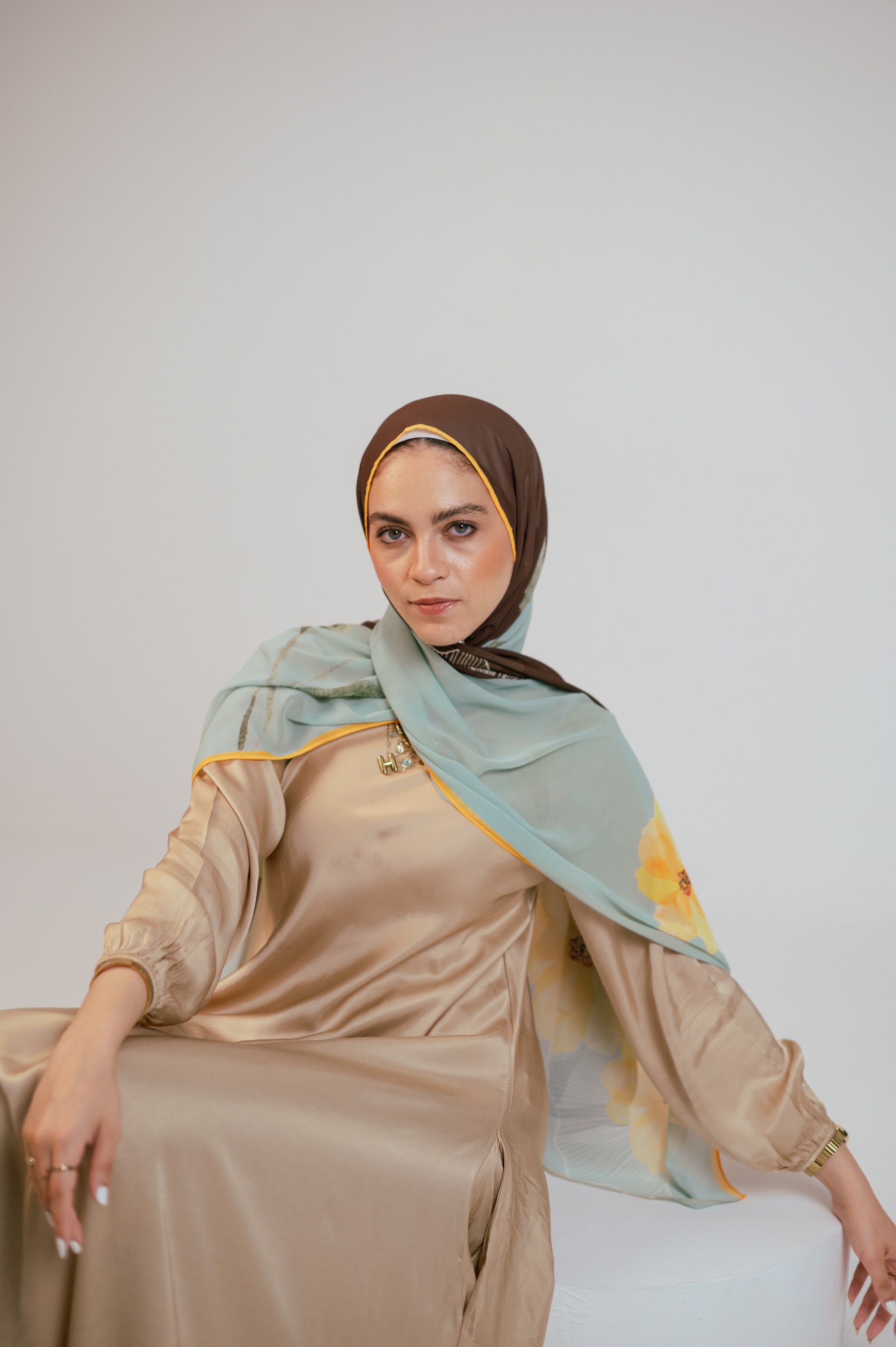 Model wearing the Terra Soleil luxury chiffon hijab styled in a soft front drape, showcasing the aqua, brown and yellow floral design.
