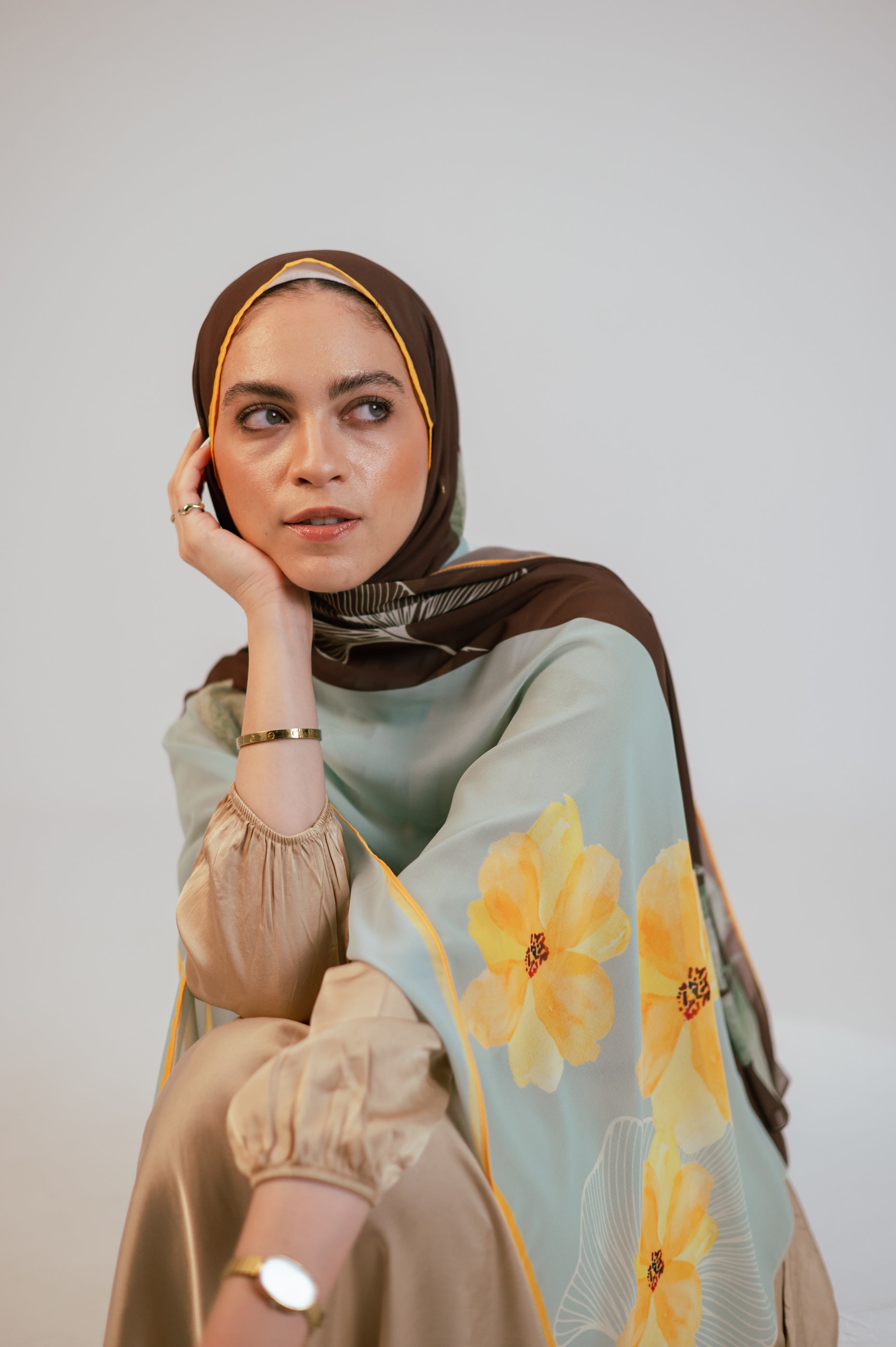 Soft side-profile shot of the model wearing the Terra Soleil luxury chiffon hijab, highlighting the elegant floral artwork and airy drape.