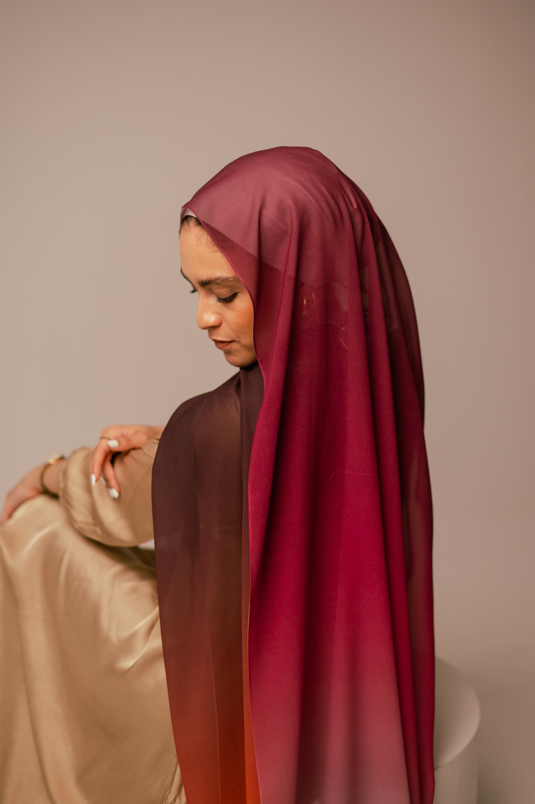 Model looking down while showing the long, flowing gradient of the Wisteria Sunset chiffon hijab.
